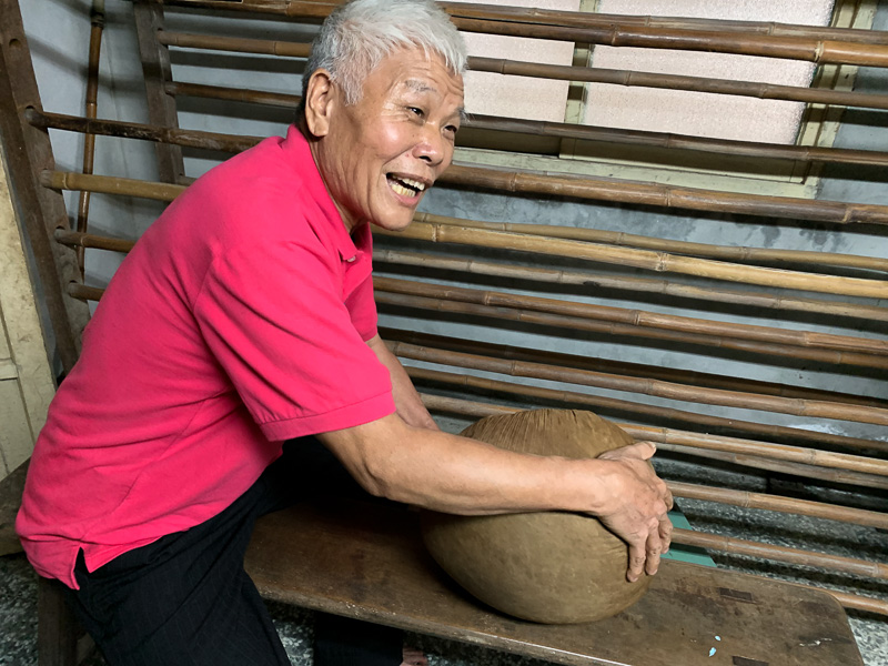 A tea farmer holds a ball of rolled tea.