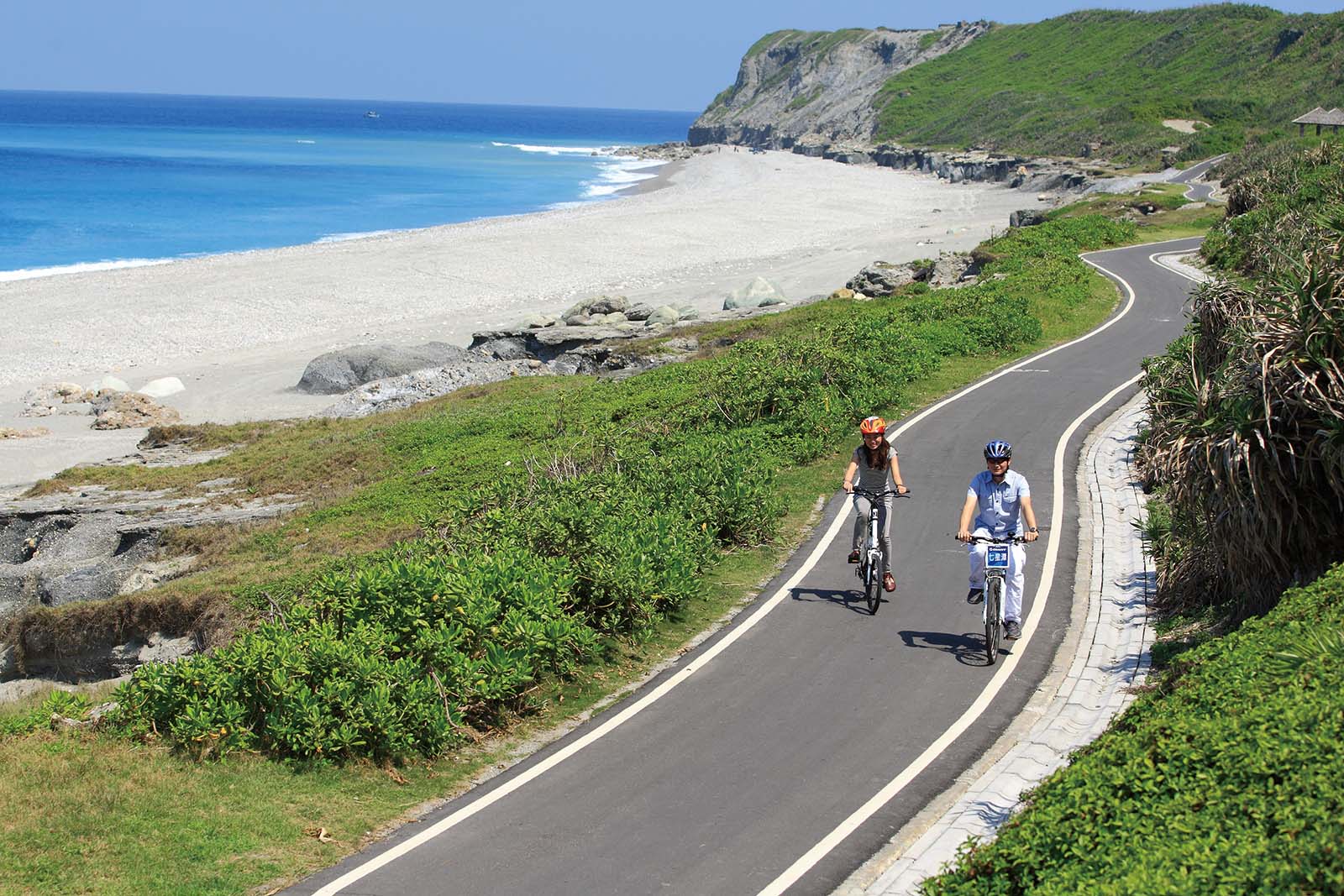 A pair of cyclists bike along the bicycle path next to Qixingtan Beach