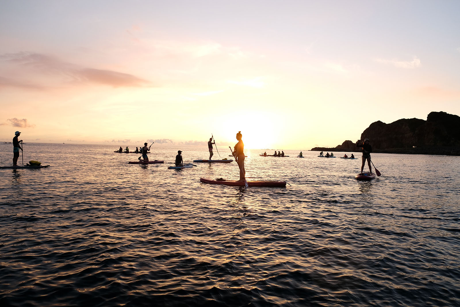 A group of tourists views the sunrise from their standup paddleboards just off the coast of Jiufen.