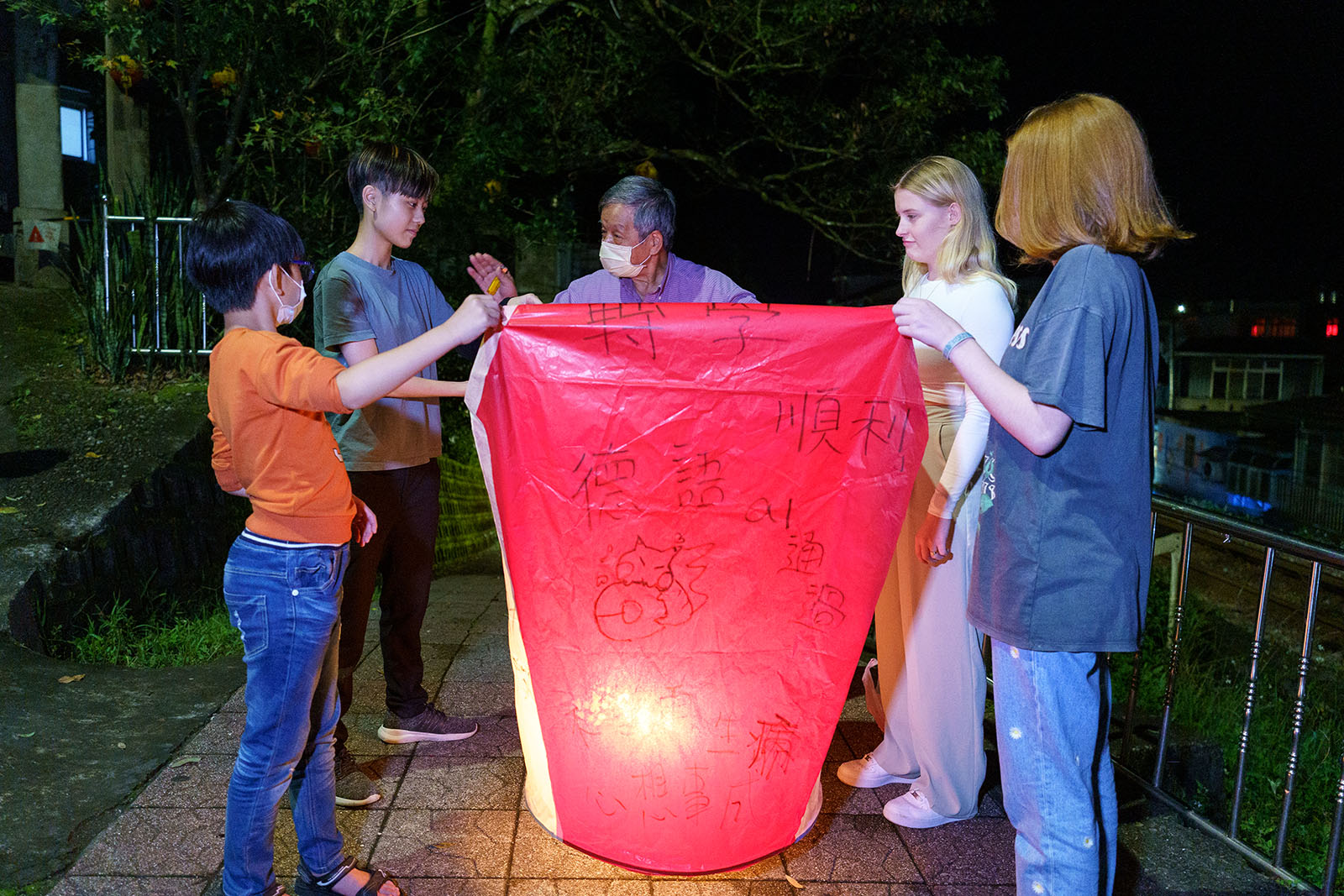 A group of tourists prepares to launch a sky lantern with their wishes in Pinglin Old Street.