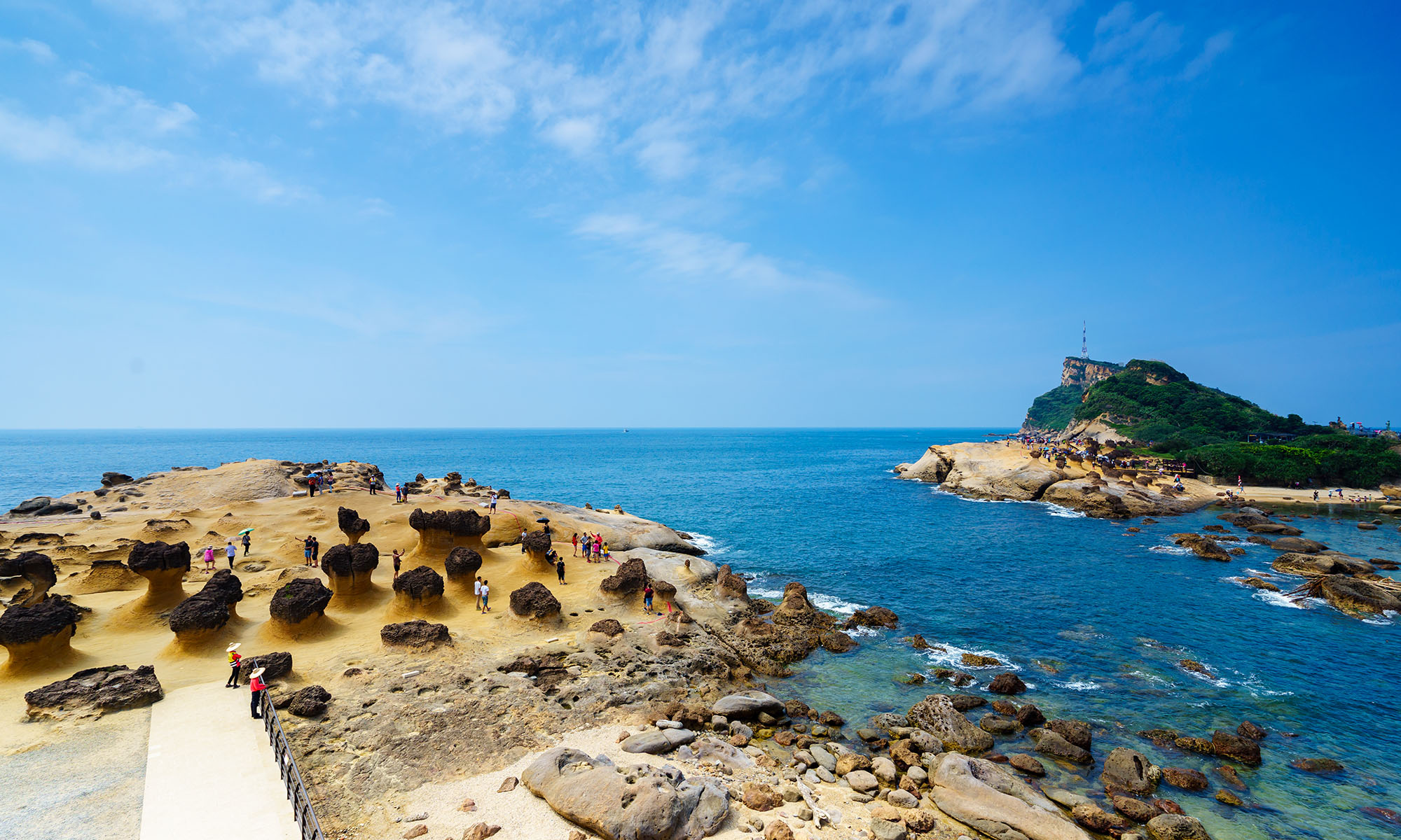 A path leads through the rocky outcrops of Yehliu Geopark and a tidal pool.