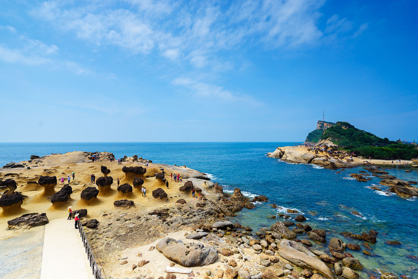 A path leads through the rocky outcrops of Yehliu Geopark and a tidal pool.