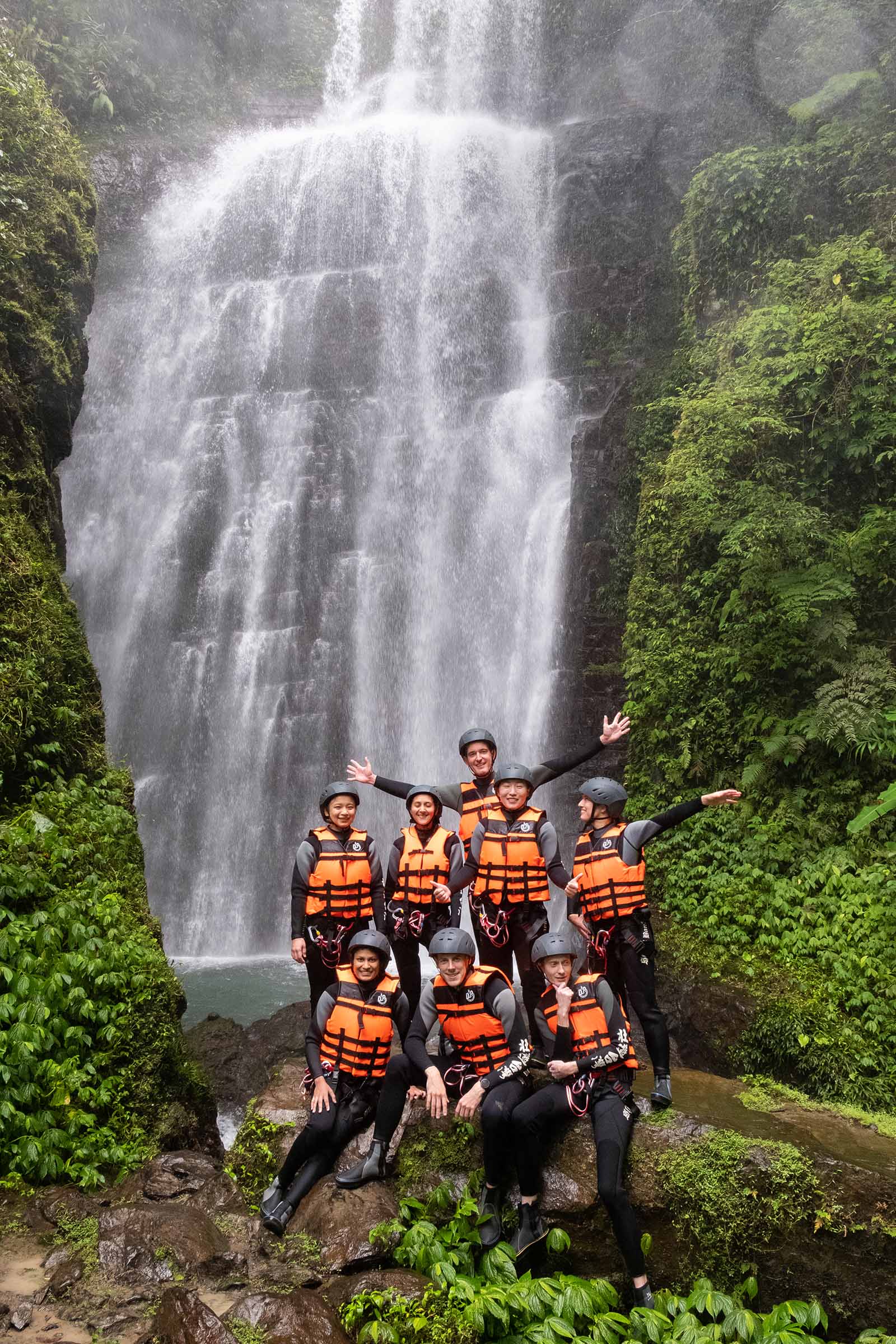 A river tracing tour group stands under the majestic Yuemeikeng Waterfall in Yilan's Wufengqi Scenic Area.