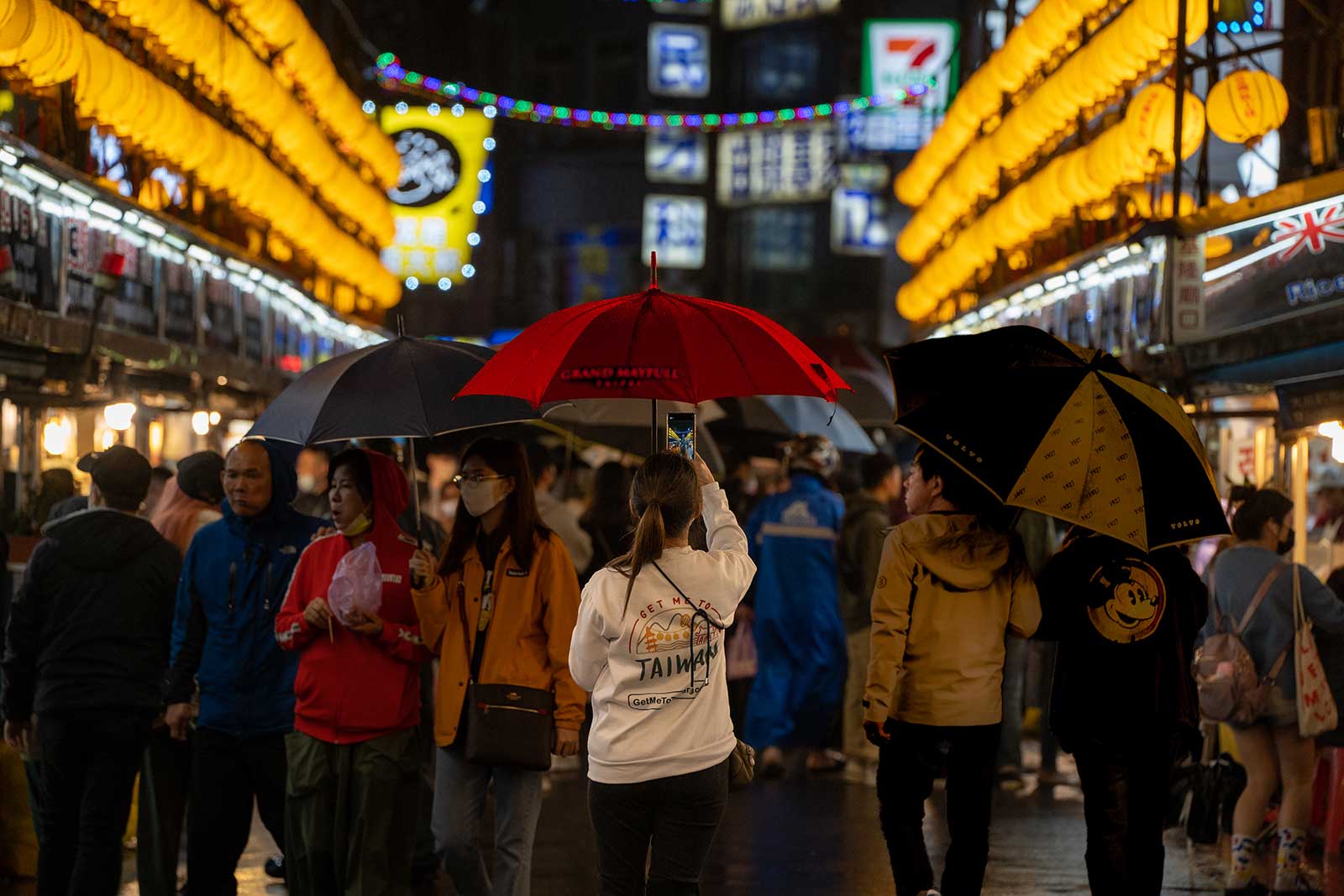 A tourist takes a photo in the middle of a busy street in a night market in Taiwan.