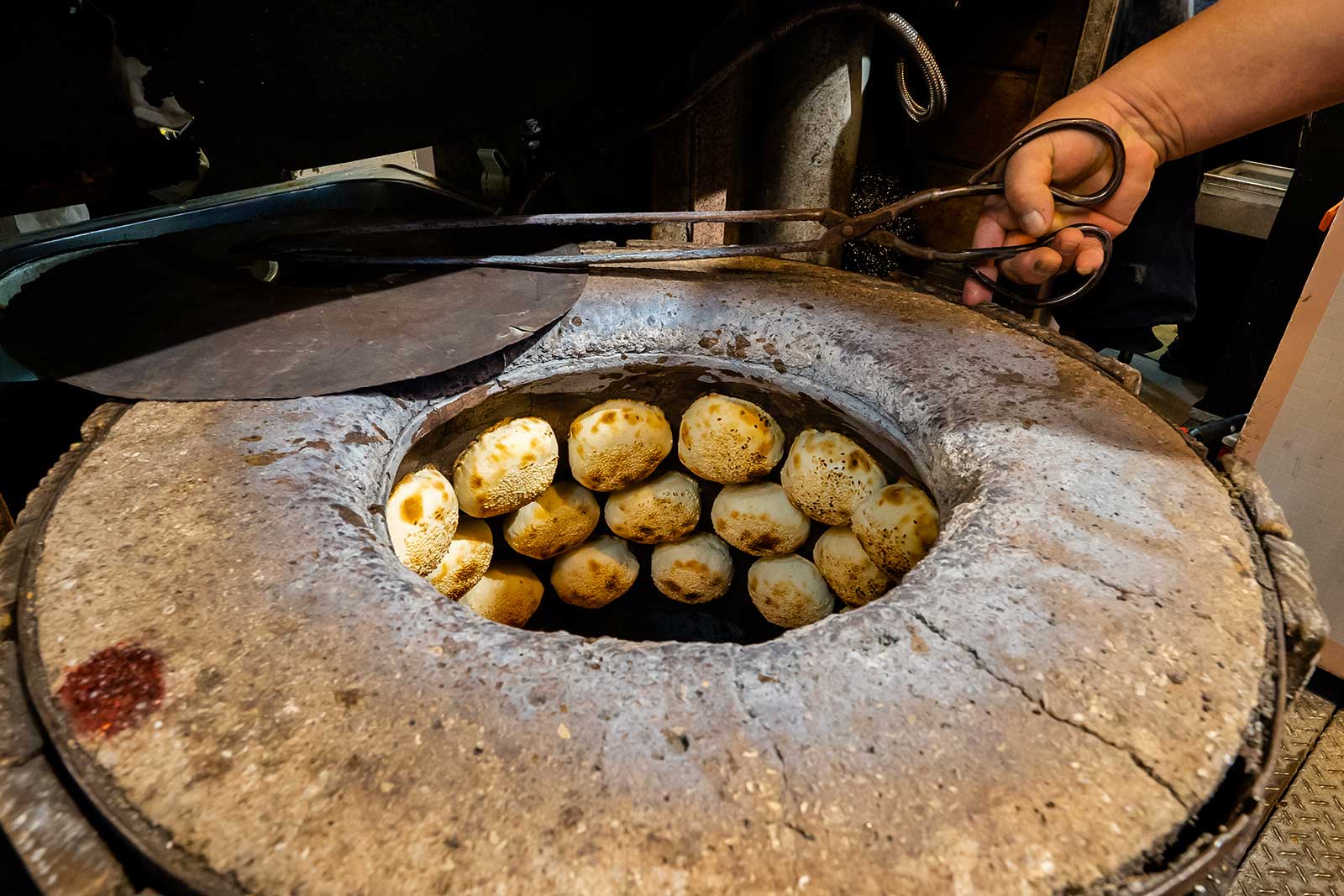 Oven-baked black pepper buns are cooking in a stone oven on the street.