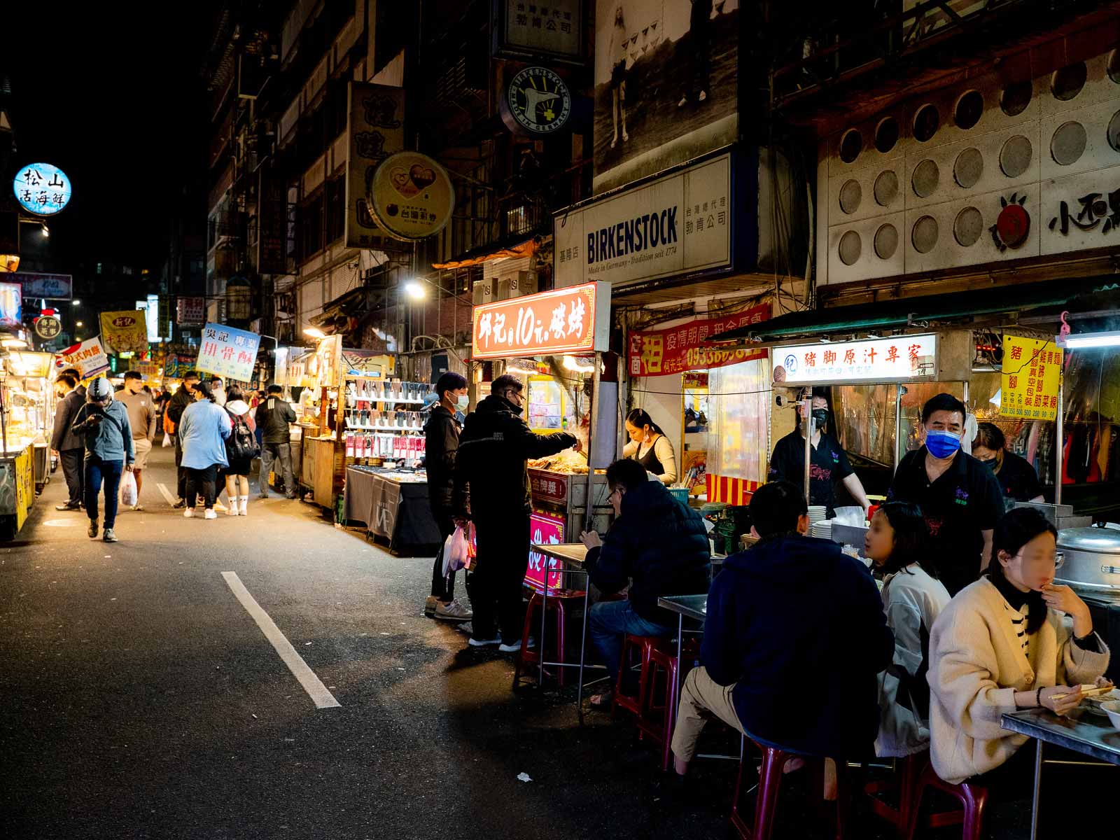 Food stands, tables and chairs line one side of the street in Keelung Night Market.