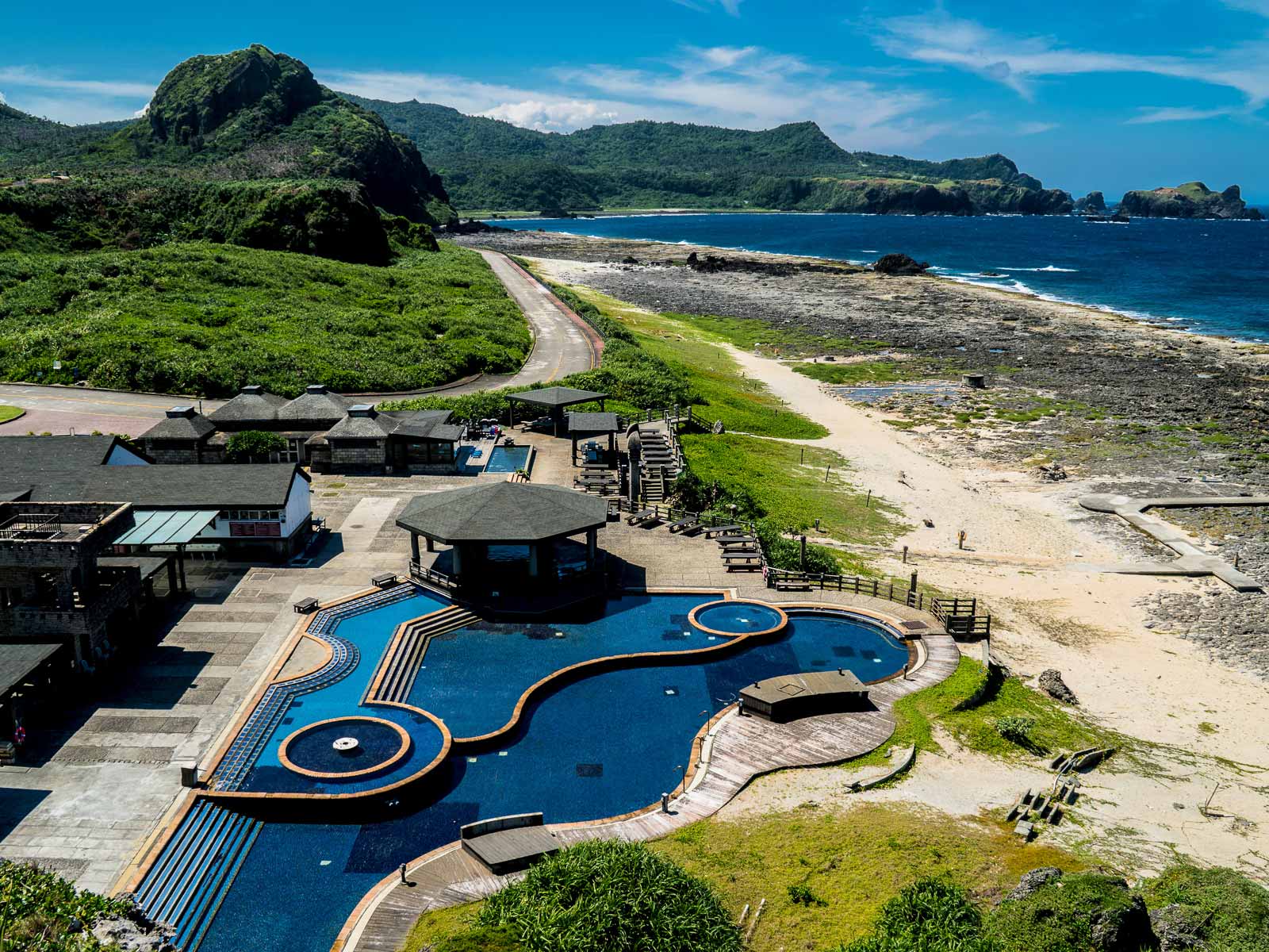 Hot spring pools lay next to the coast made up of volcanic rock and golden sand.