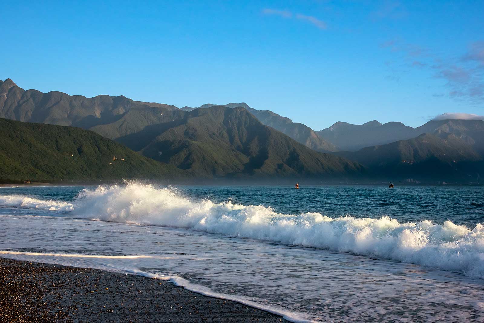 The mountains of Taroko National Park glow in the early morning sun during sunrise at Qixingtan Beach.