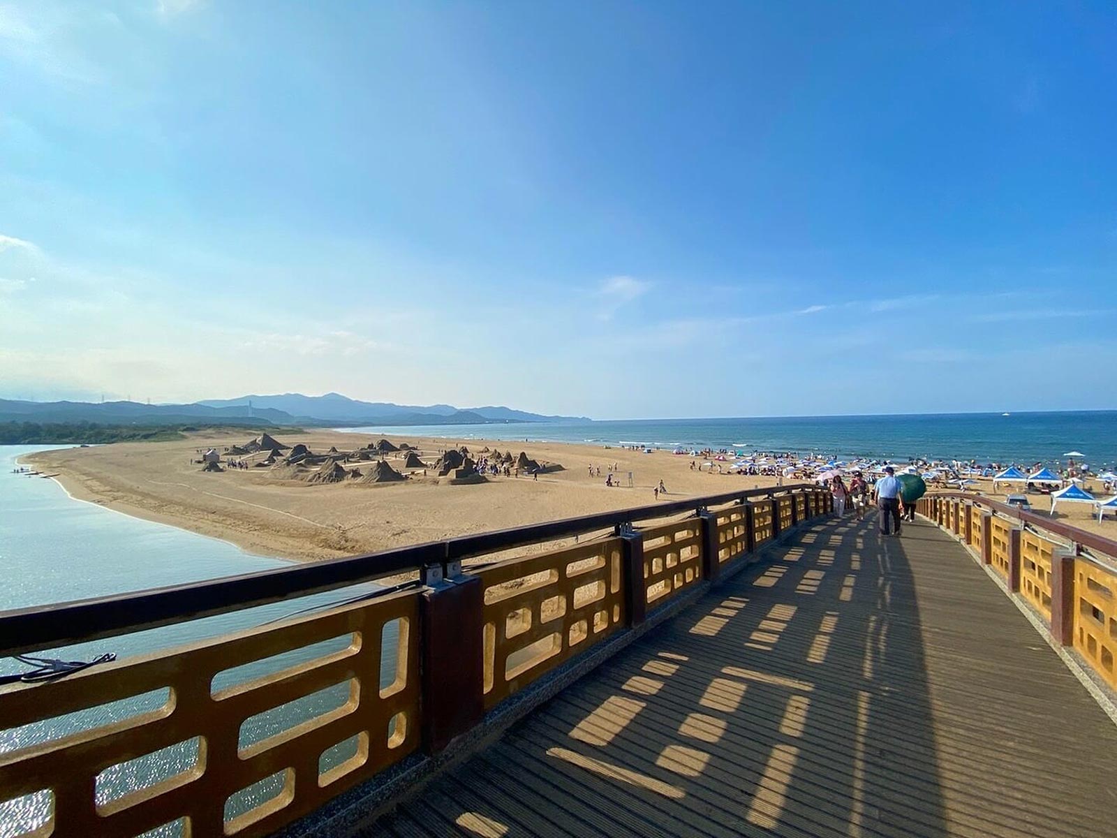 An expansive view of Fulong Beach and the mountains and coastline of the North Coast from a pedestrian bridge.