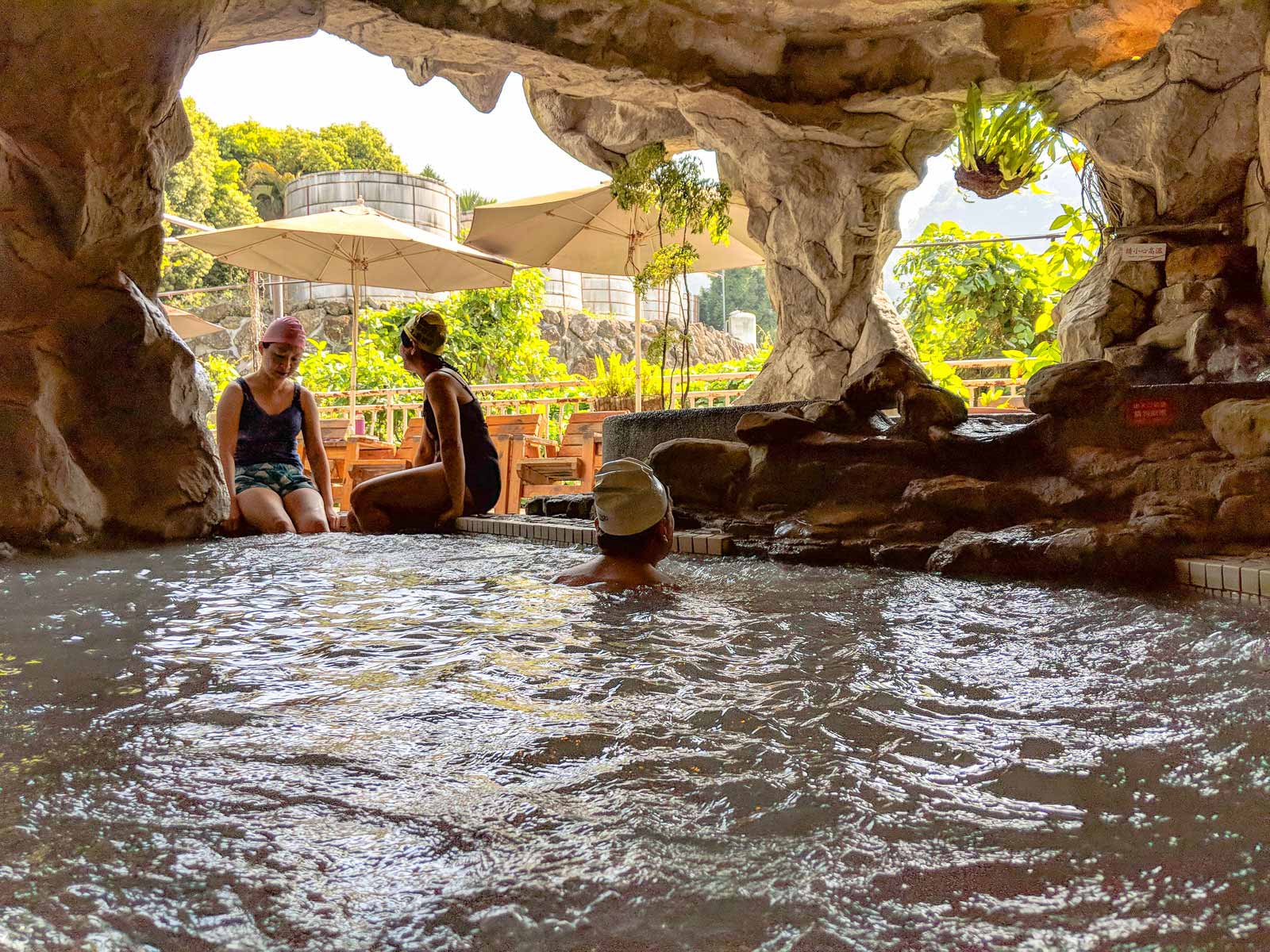 Bathers enjoy an open-air hot spring within a cave-like structure.