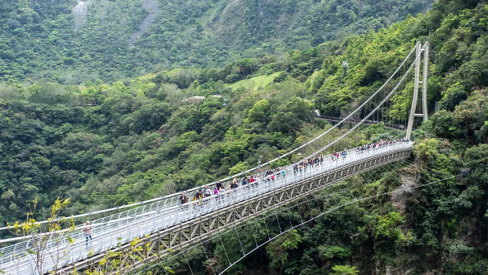 The Buluowan Suspension Bridge is visible from above; the turquoise water of Taroko Gorge can be seen flowing far below.