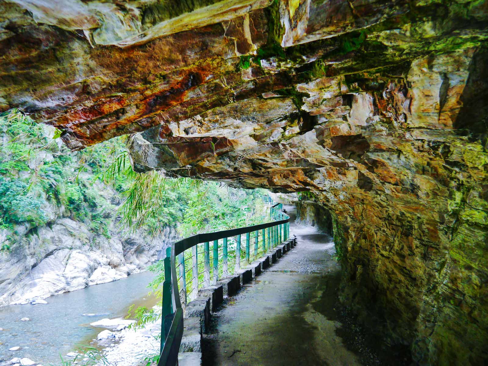 A portion of the Shakadang Trail can be seen carved into the wall; to the left is a steep drop into Shakadang River.