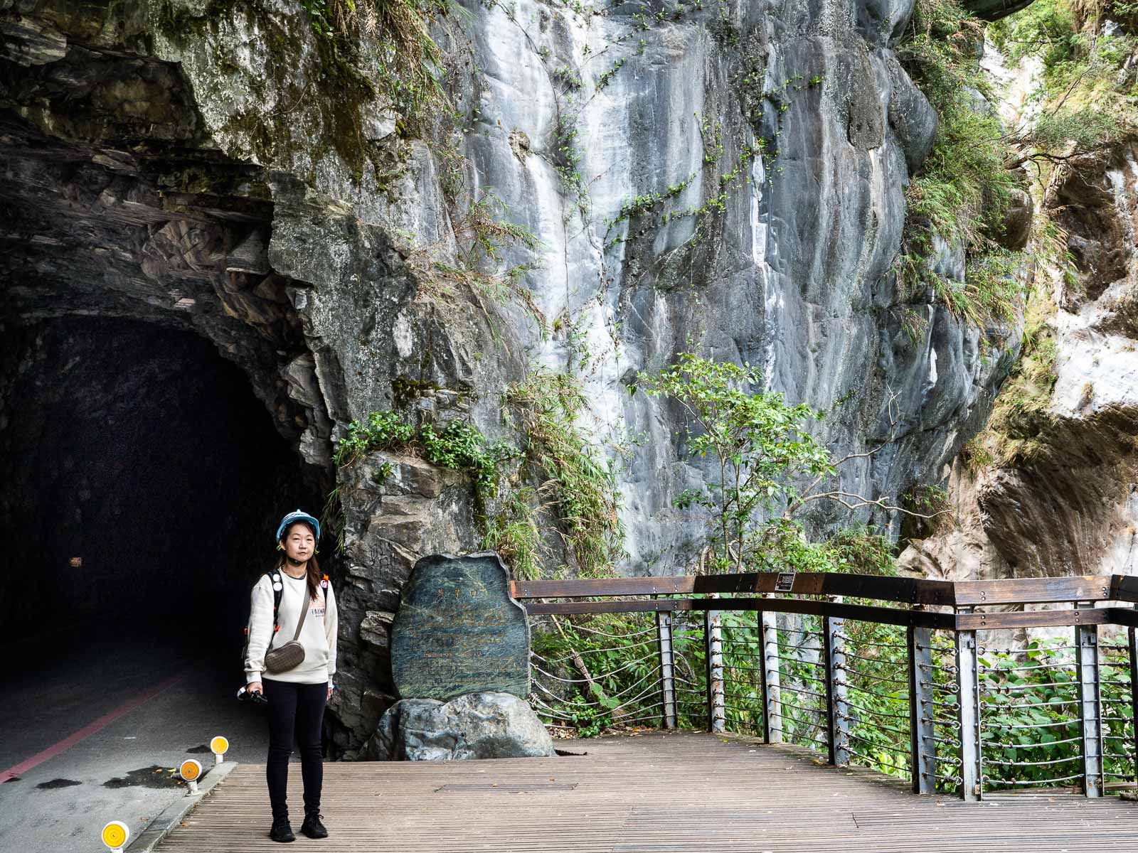 A tourist wears a helmet while walking the Swallow Grotto Trail.