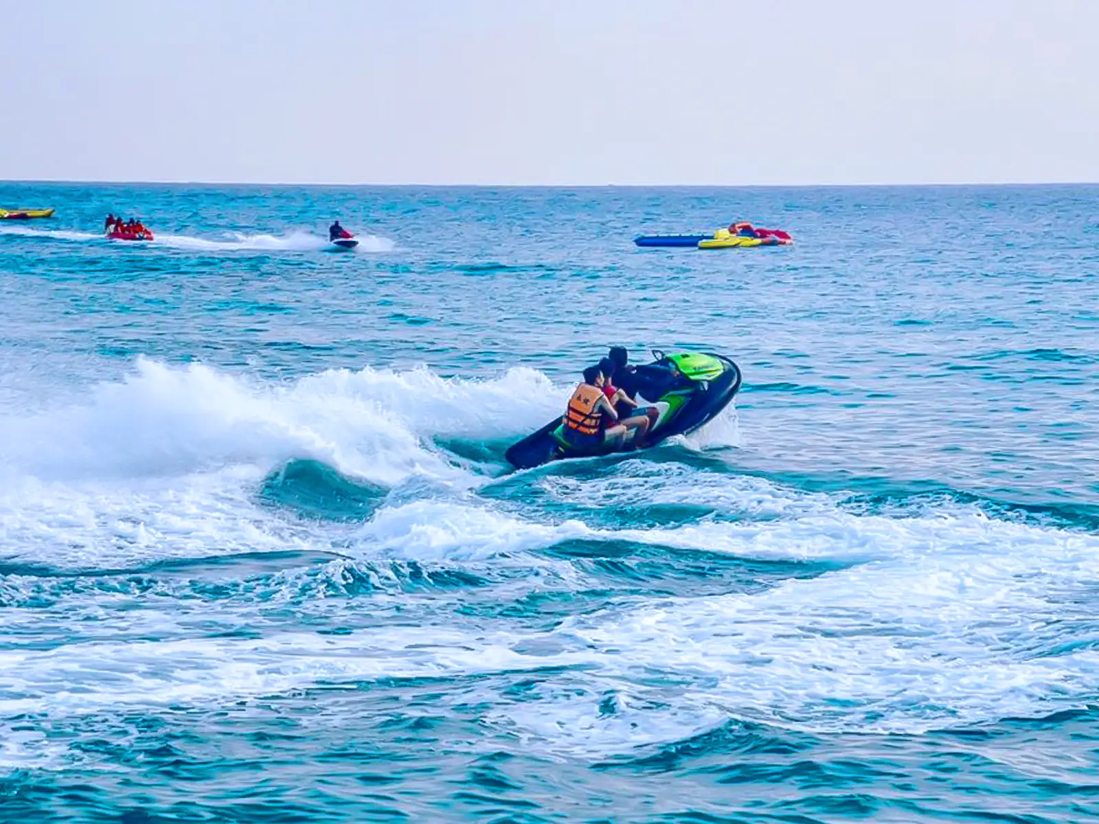 A group of jet skis race through ocean water.