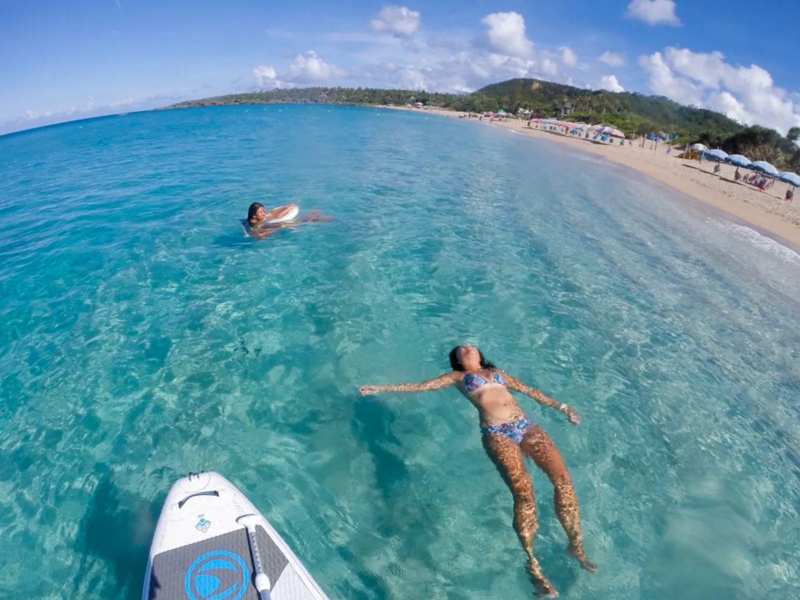 Tourists swim in the ocean at Baishawan Beach.