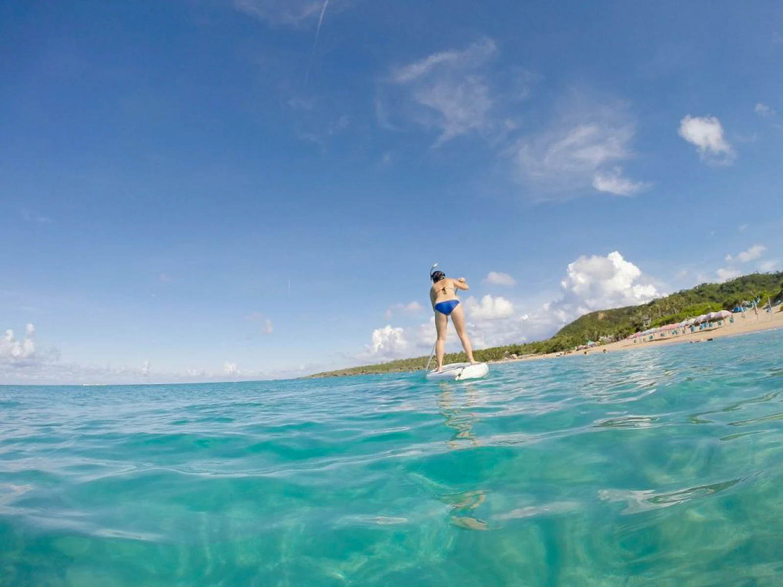 A paddleboarder struggles to find balance while standing up on her board.