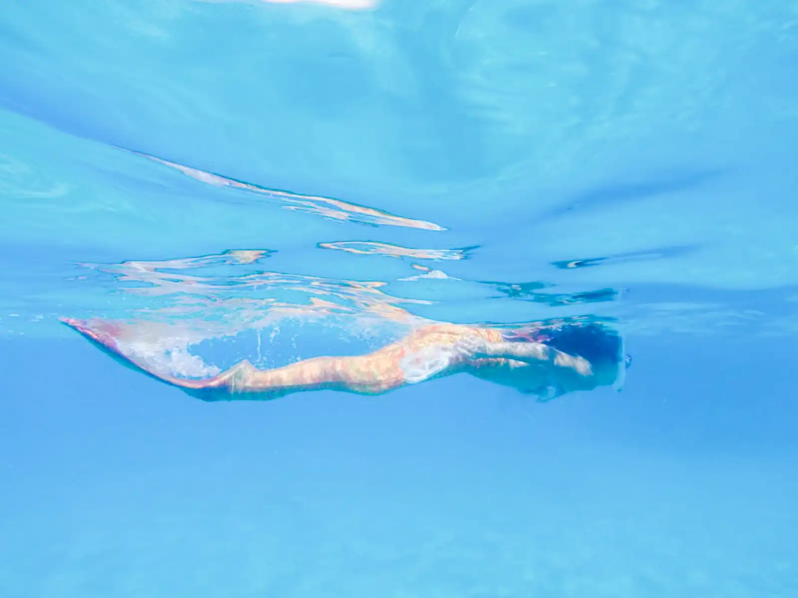 A snorkeler swims in crystal clear ocean water.