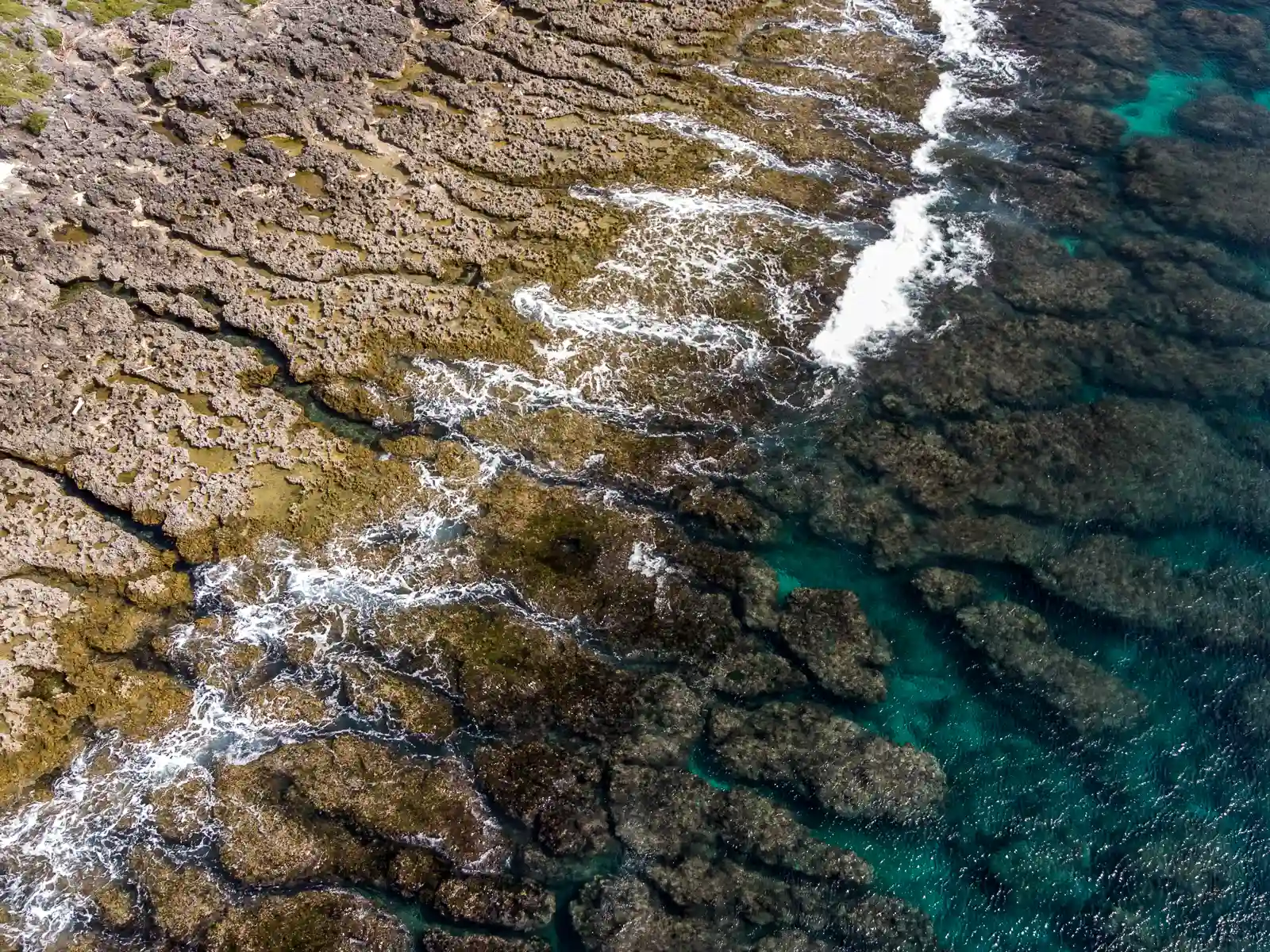 Rugged volcanic rocks emerge from the shore on both ends of the beach.