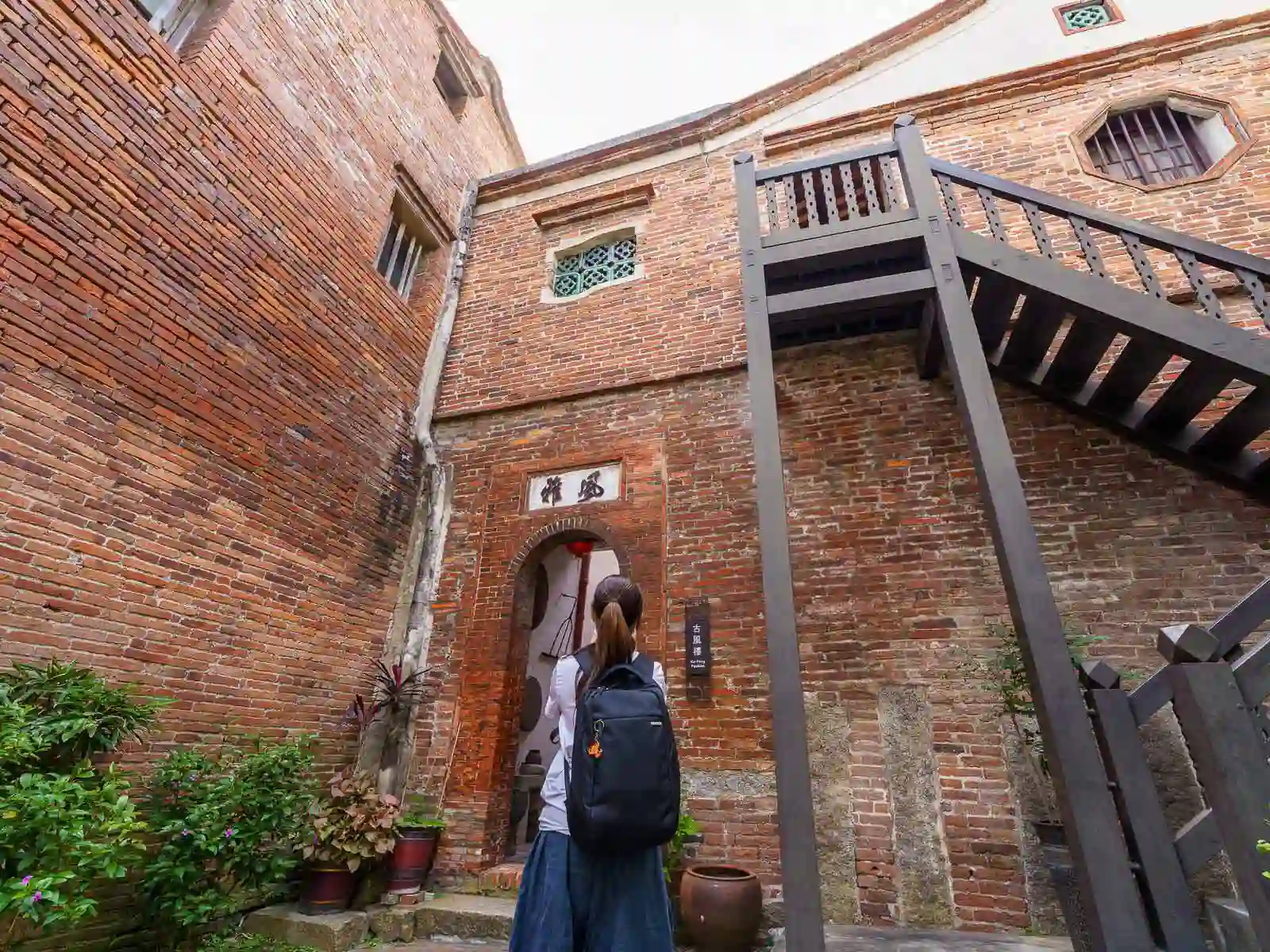 A tourist looks on at a red-brick doorway in a courtyard of the museum.