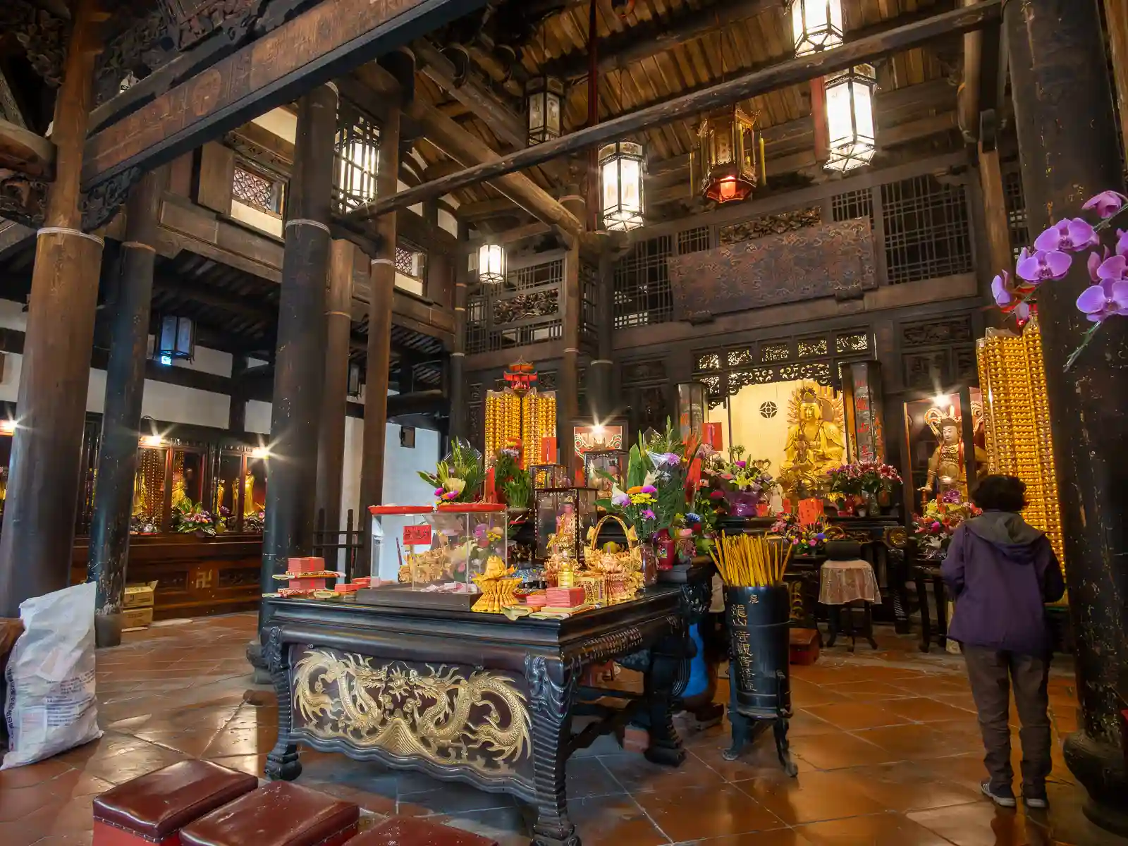 The interior of Lukang Longshan temple has golden effigies, wooden lanterns, and offerings on display.