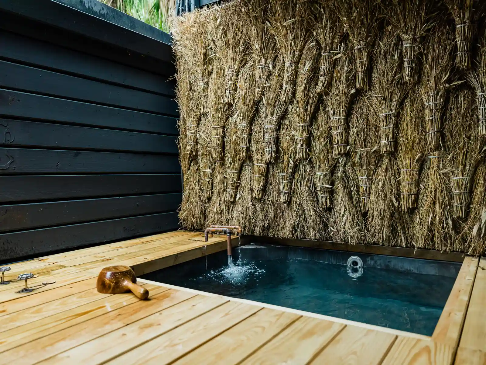 Walls of a bathing area are decorated with bunches of dried grass.