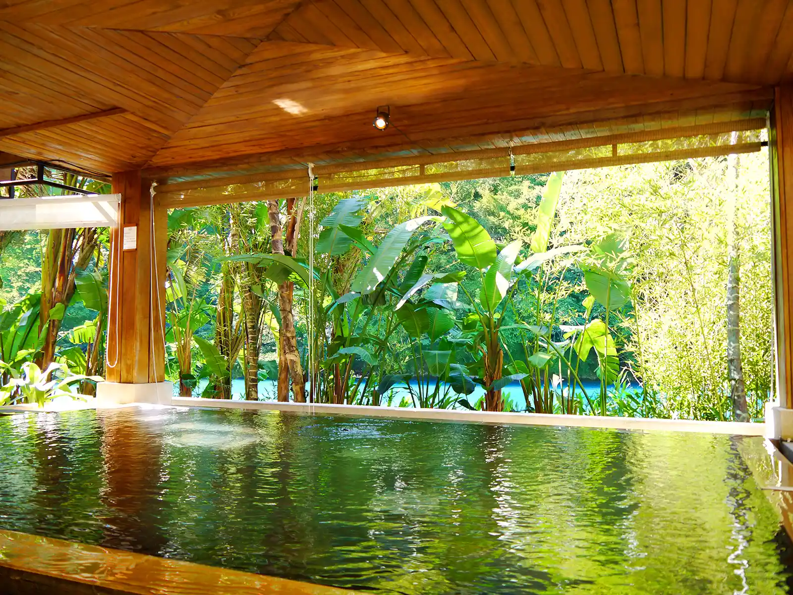 Crystal clear river water can be seen from a covered hot spring pool.