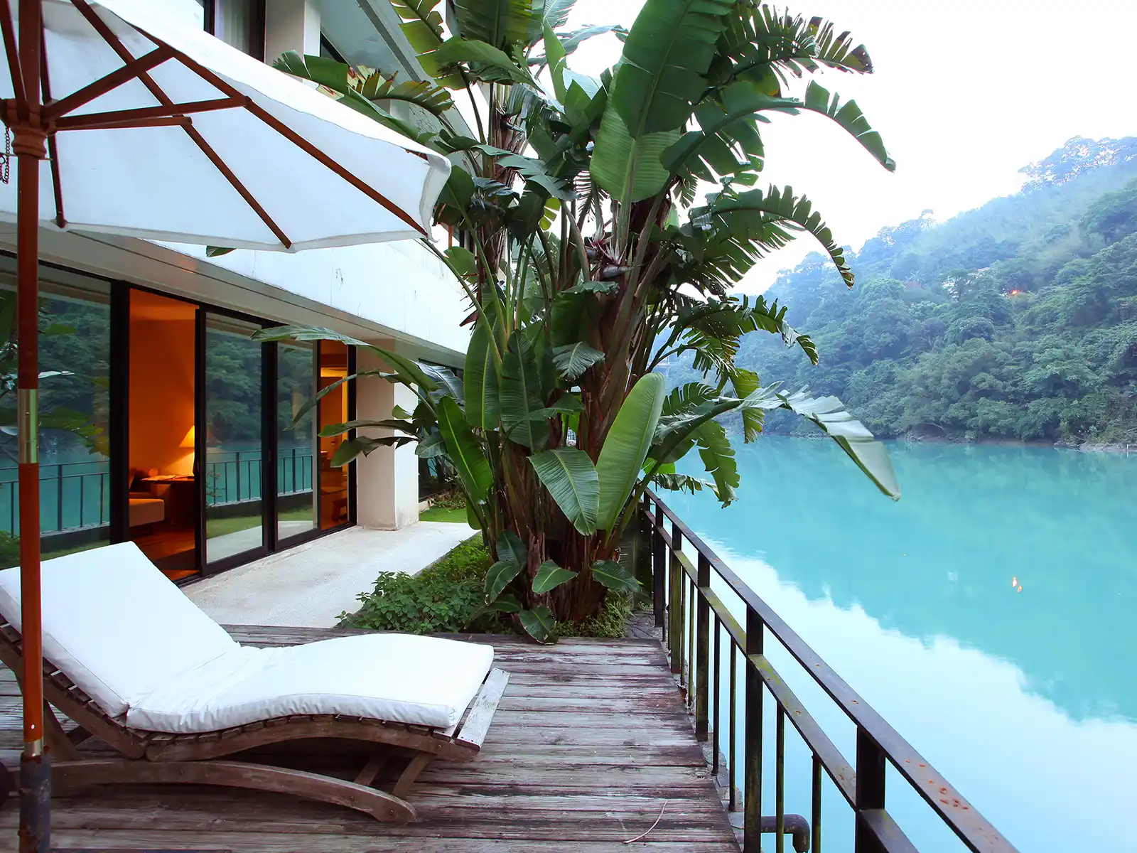 A lakeside balcony with a lounge chair is meters from the water.