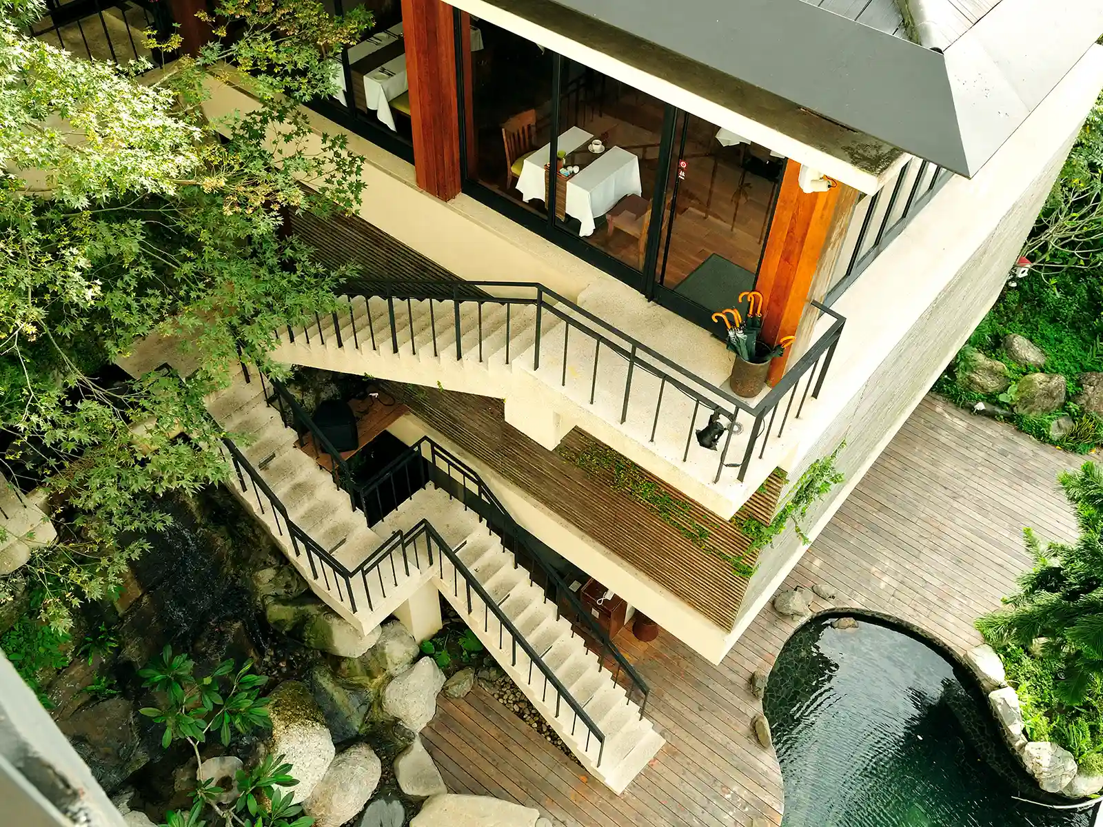 An exposed stairwell, slightly obscured by trees, climbs the outside of a building.