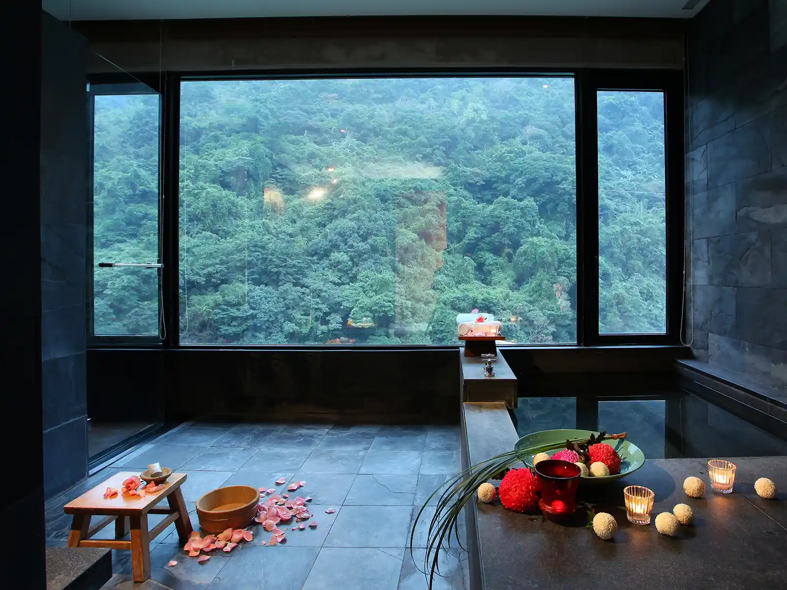 A private hot spring room with tub and floor-to-ceiling windows.