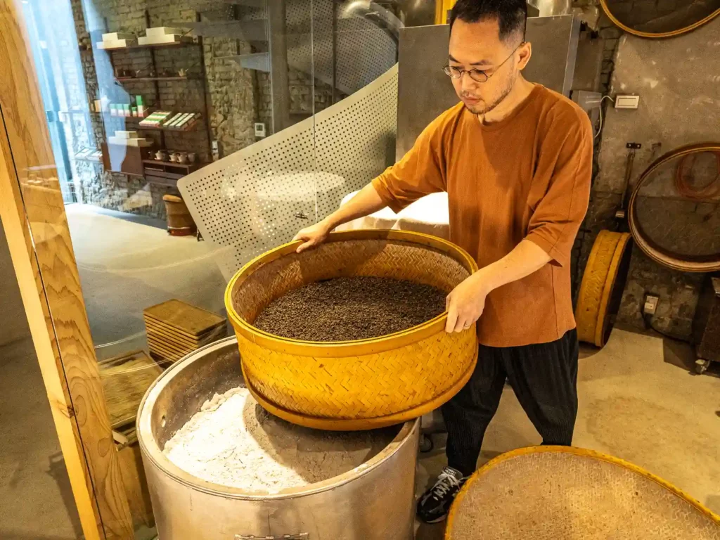 A batch of tea leaves is being moved inside the front roasting area.