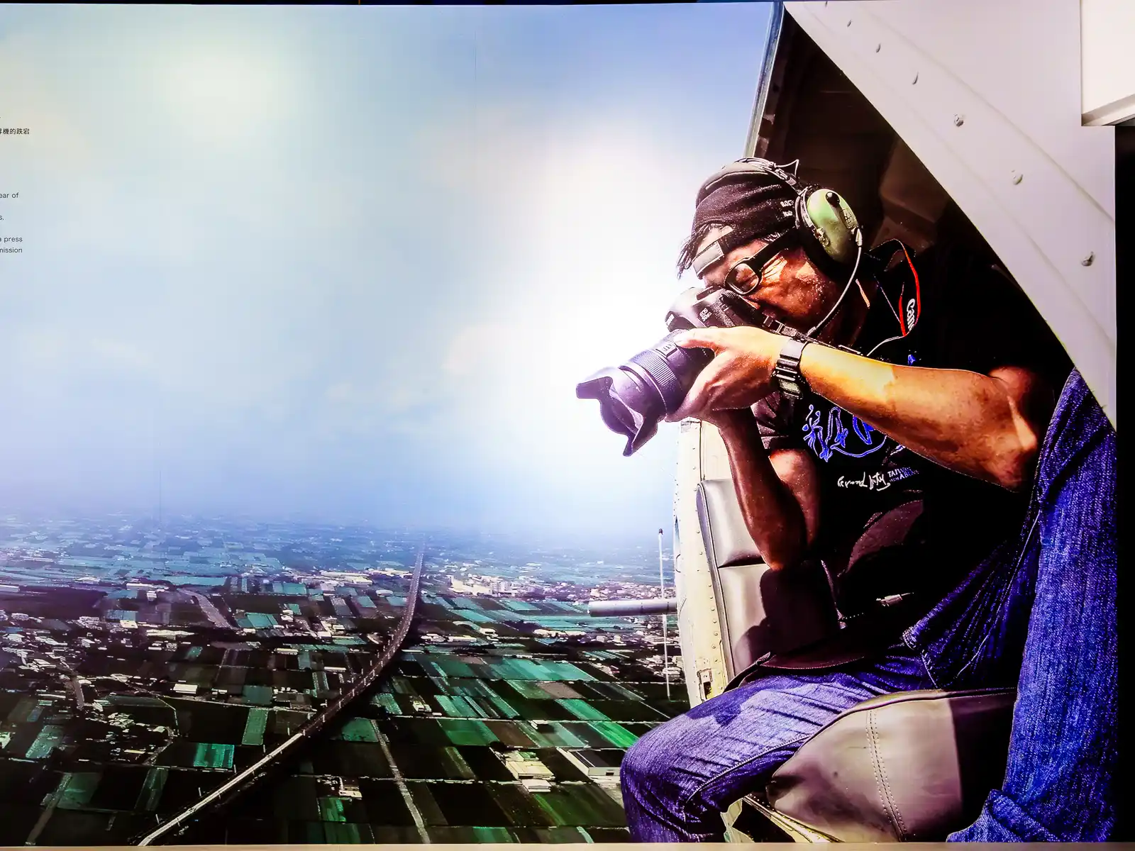 A portrait of Chi Po-lin as he takes a photograph from a helicopter door.