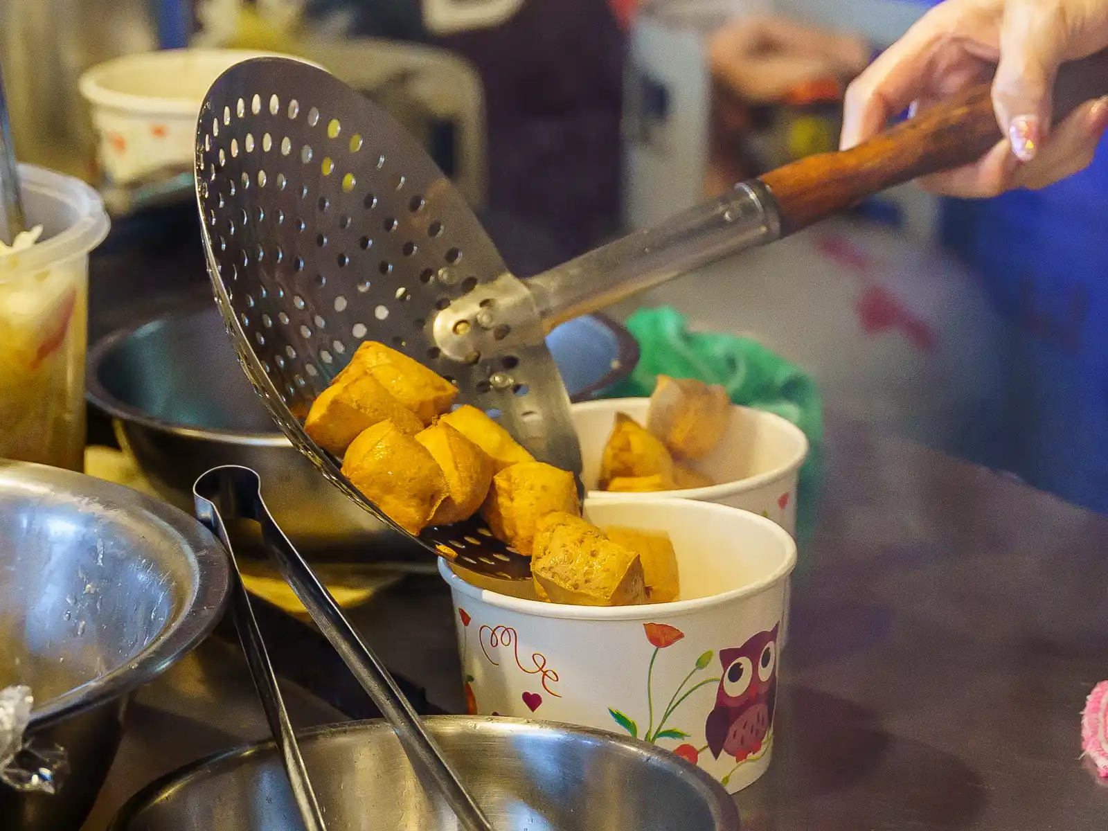 An order of stinky tofu is being packed into a take-out container.