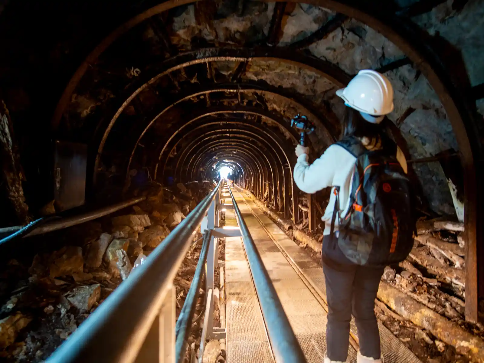 A tourist stands in Benshan No.5 Tunnel, an old narrow mining tunnel.