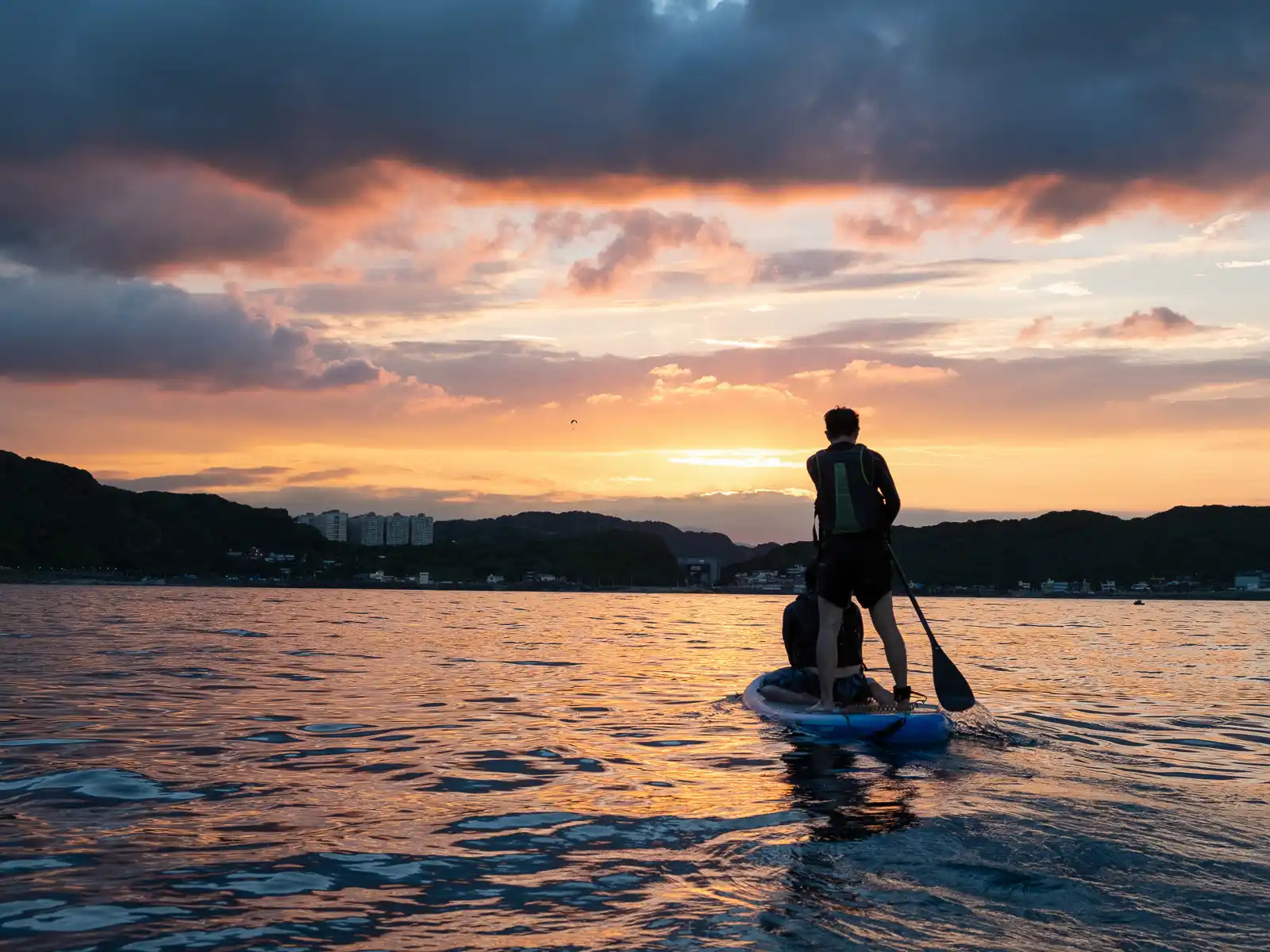 Stand-up paddleboarders paddle back to the shore after sunset.