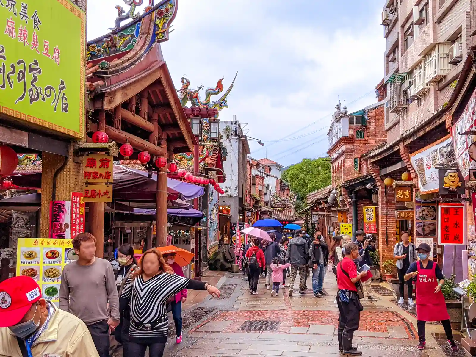 The red-brick-lined Shenkeng Old Street is packed with tourists carrying umbrellas on a rainy day.