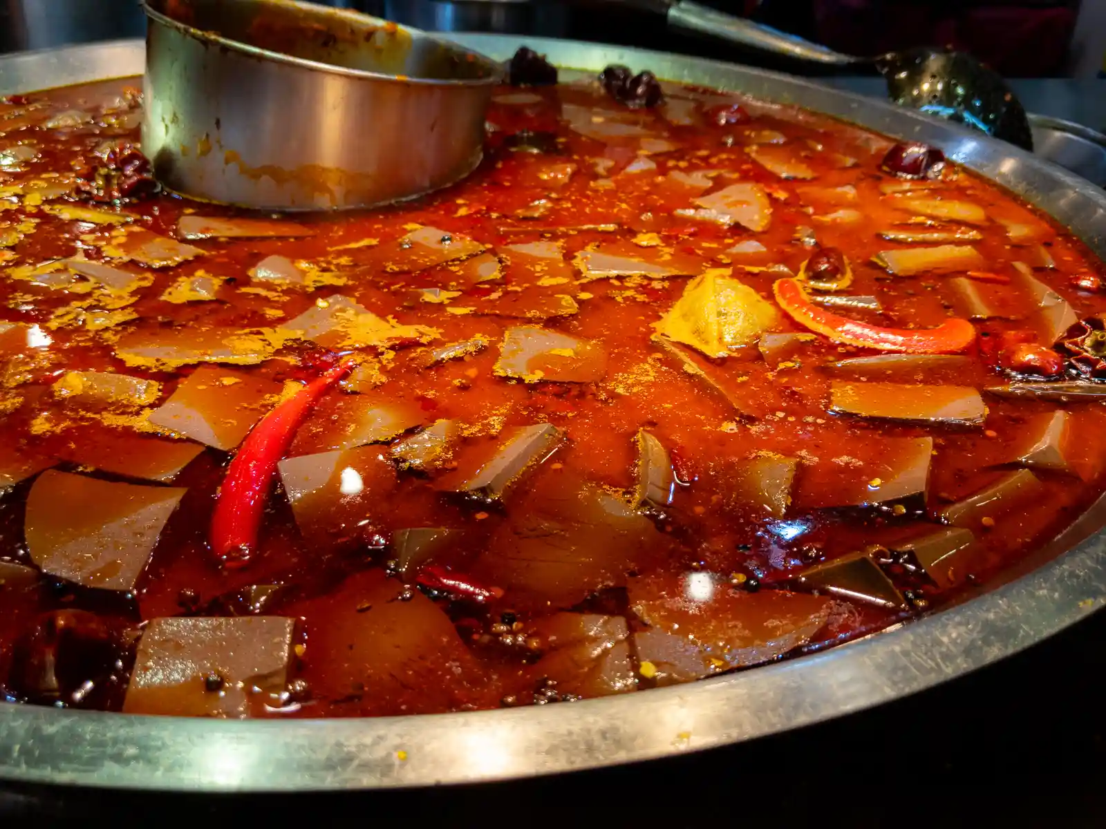 A large cooking pot contains a spicy soup with congealed duck's blood and stinky tofu.