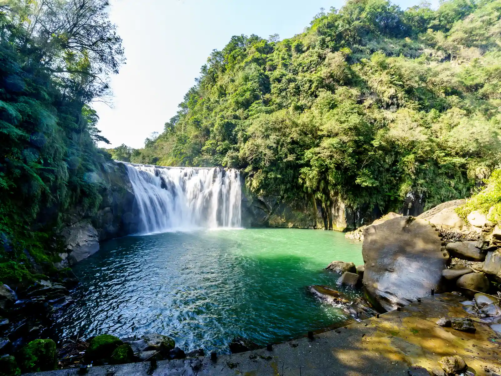 The horseshoe-shaped Shifen Waterfall plummets into a deep green bowl-shaped pool.