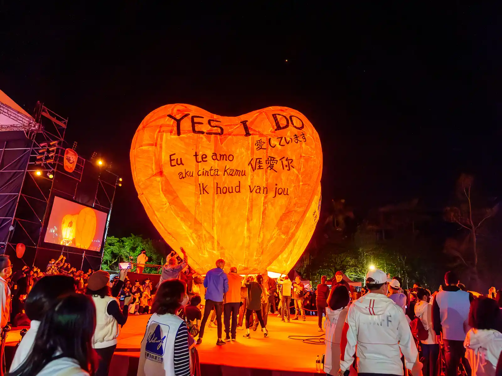 One of the large heart-shaped special event lanterns is being held down before release.