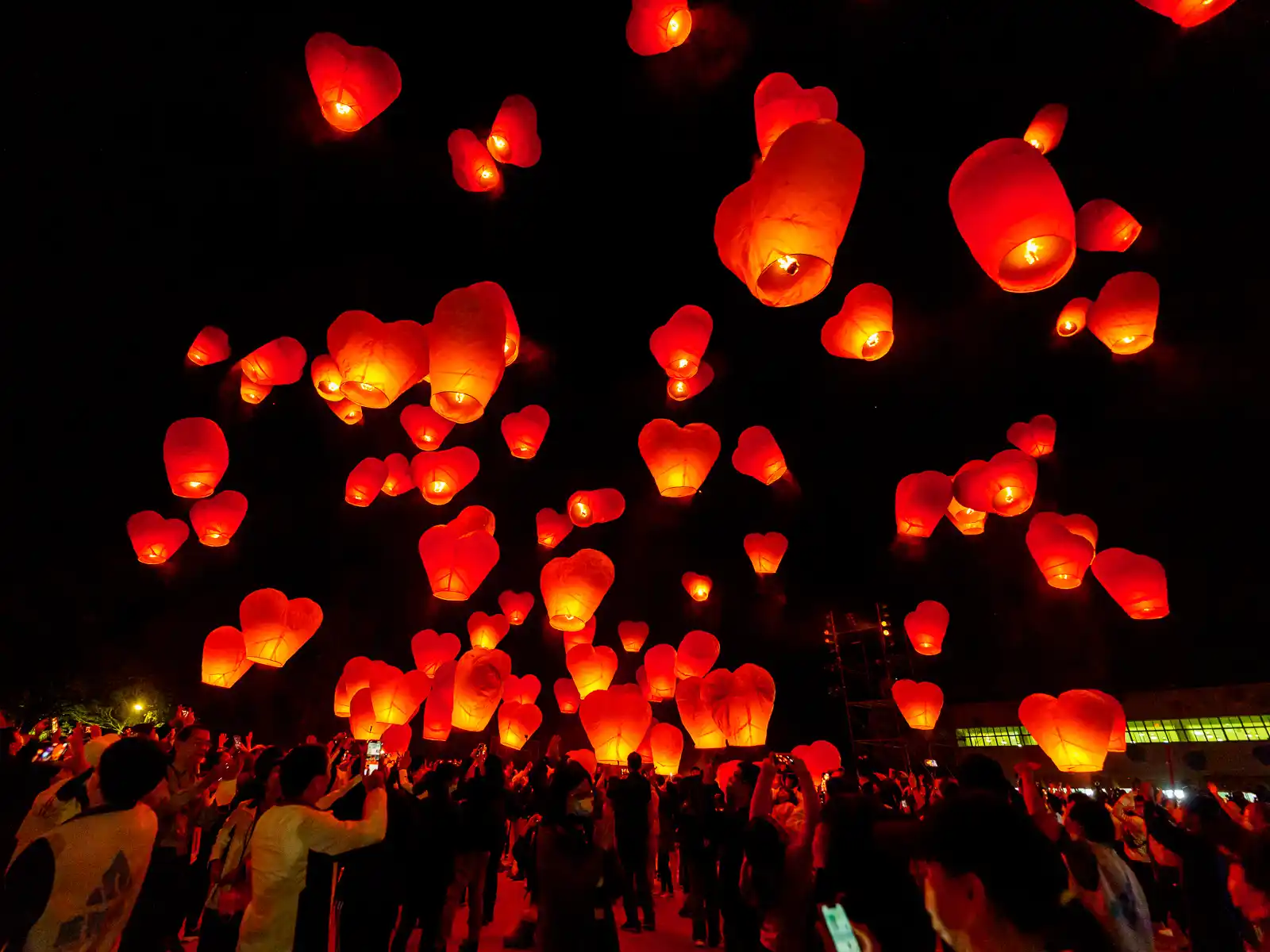 Glowing red lanterns that have just been released rise up above the crowd at the Pingxi Lantern Festival.