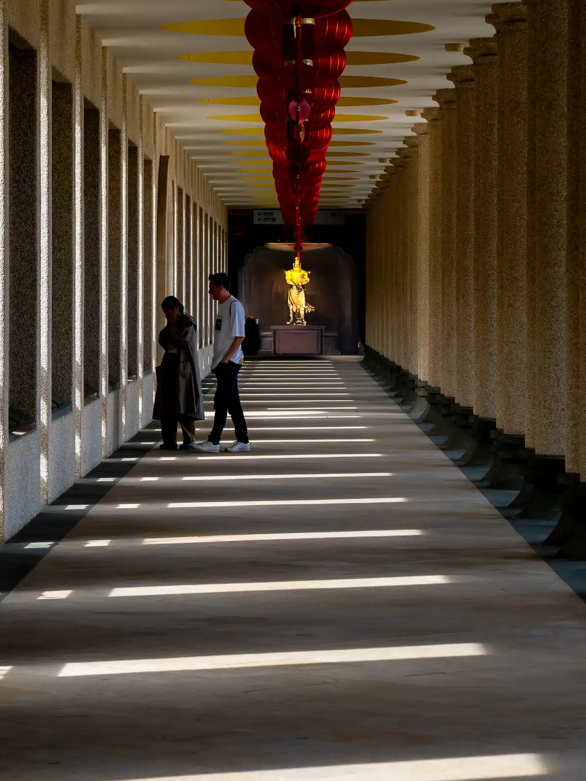 Tourists visit a covered arcade made of stone.