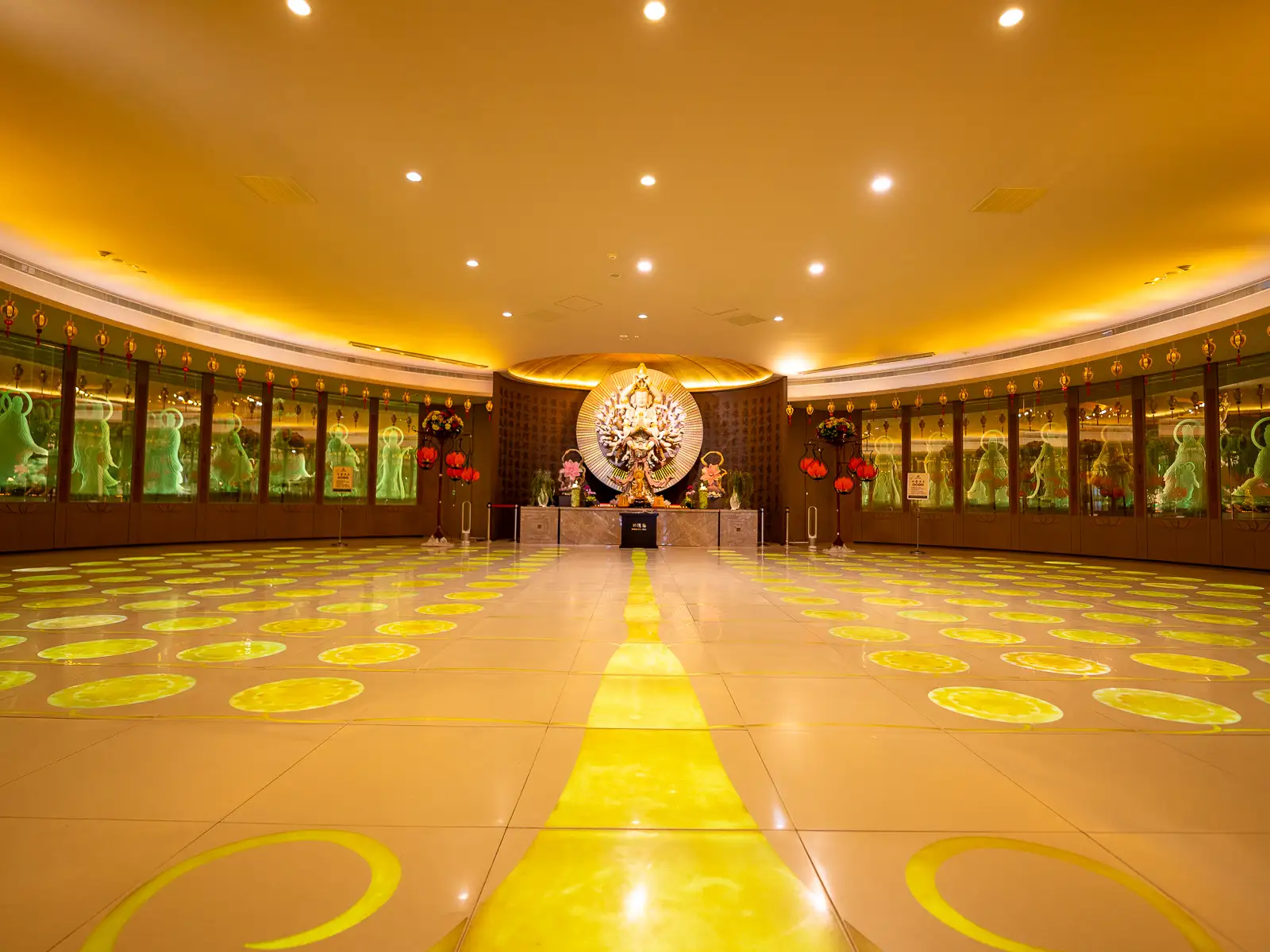 A Thousand-Armed, Thousand-Eyed Avalokitesvara Bodhisattva statue sits at the far end of a circular room.