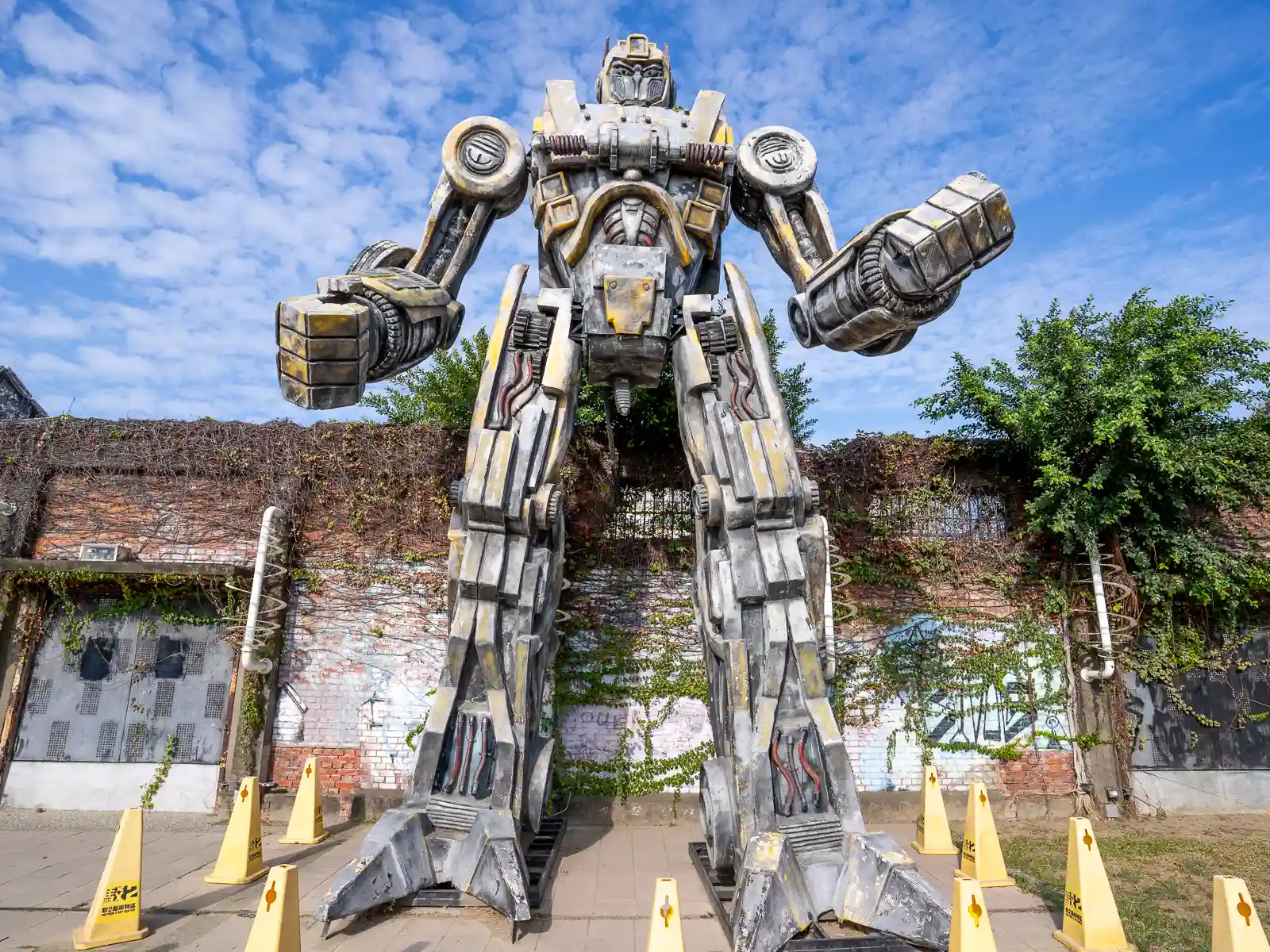 A sculpture of a giant metal transformer robot stands 3 stories tall.