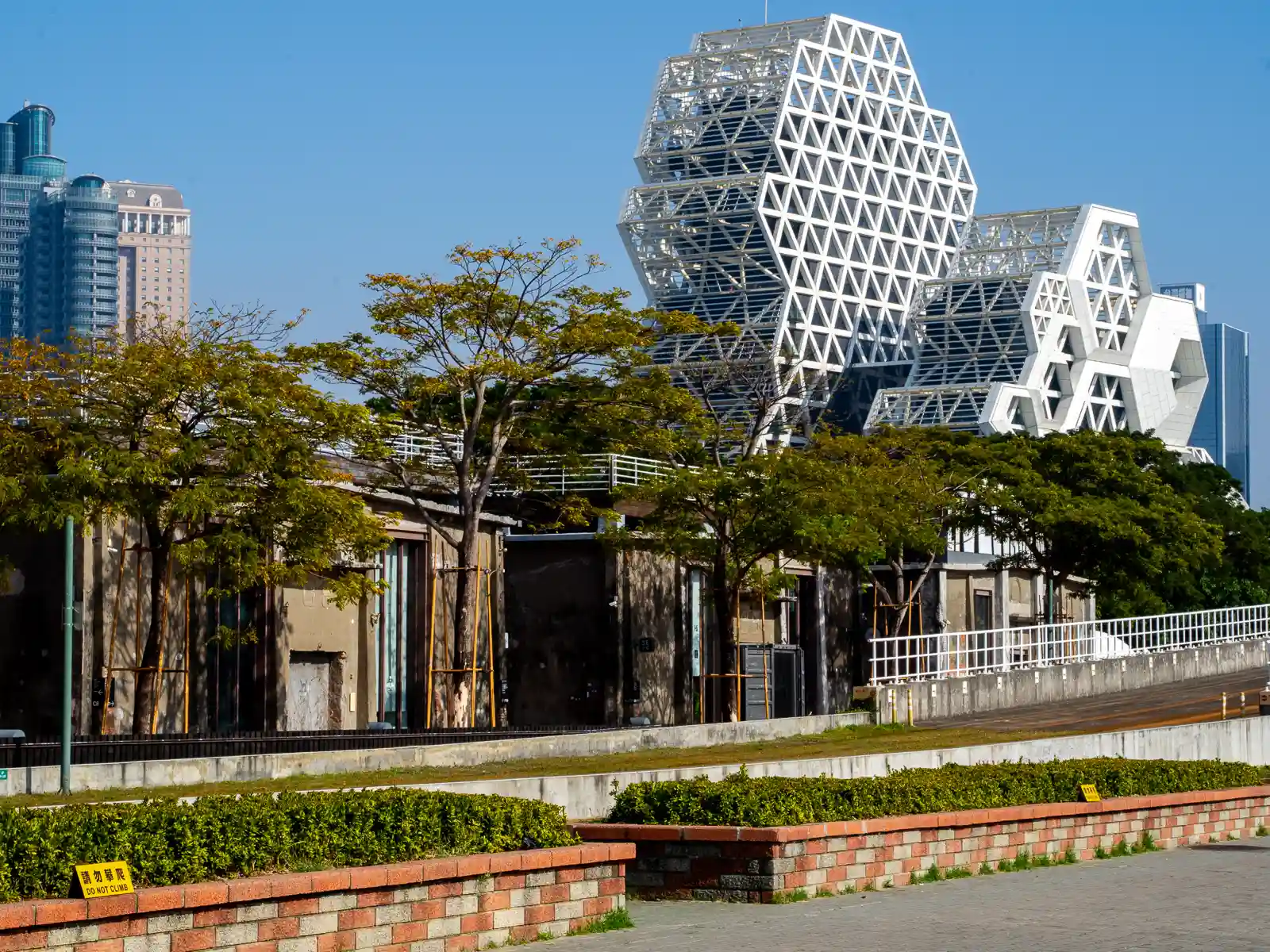 The geometric lattice exterior of the Kaohsiung Music Center can be seen above the warehouses of the Dayi Cluster.