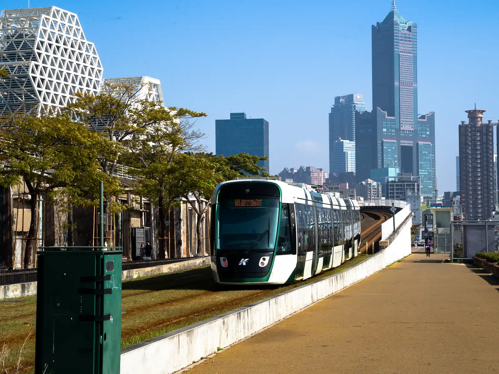 A light rail train is arriving at Pier 2 Art Center; the Kaohsiung 85 Sky Tower can be seen in the background.