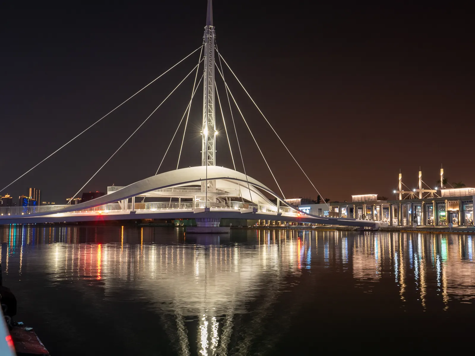 At night, the bridge, along with its smooth and flowing canopy, is illuminated with soft white light.