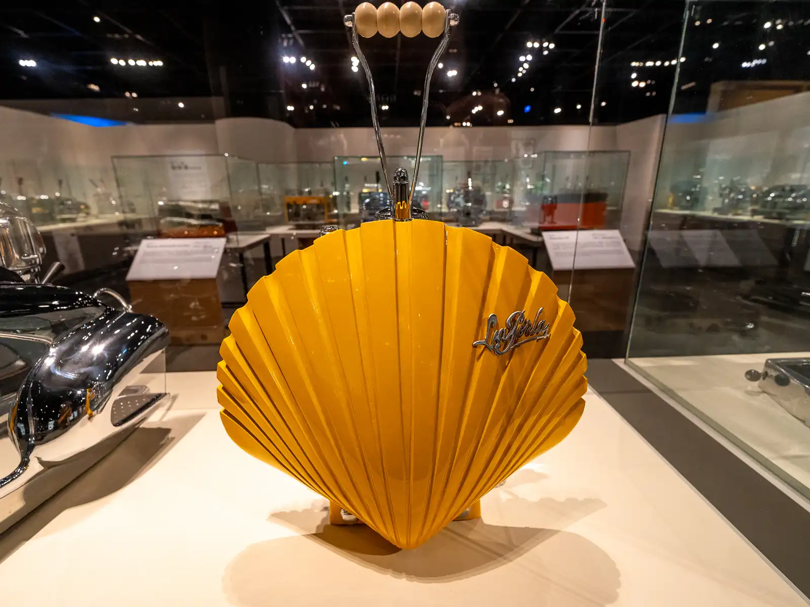 A yellow coffee maker in the shape of a shell is on display.