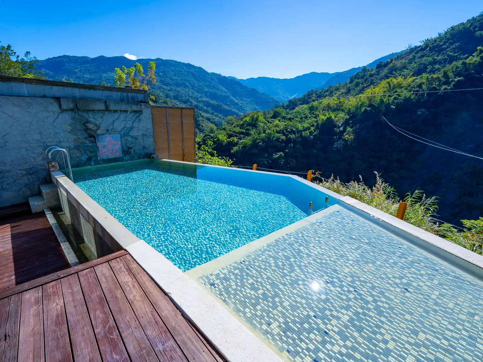 A hot spring infinity pool overlooks the surrounding forest and mountains.