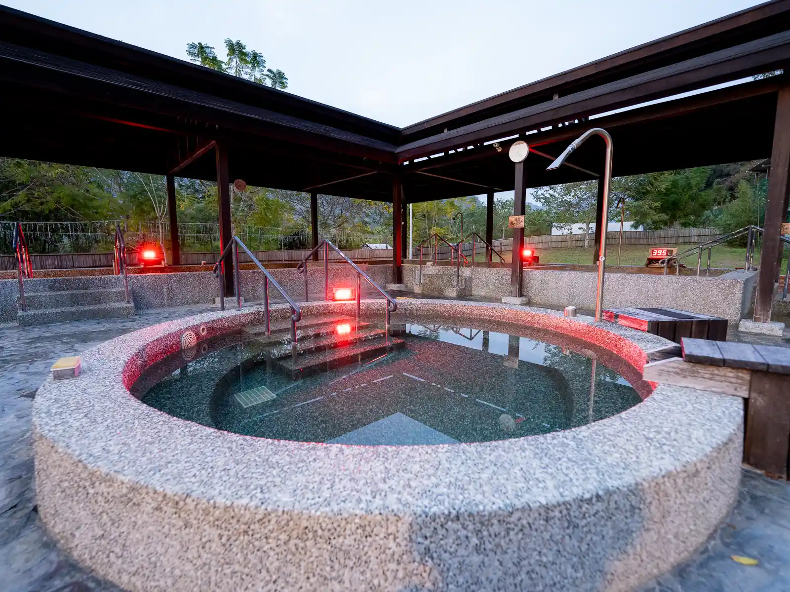 A high-pressure spa jet is aimed down at a circular hot spring pool.