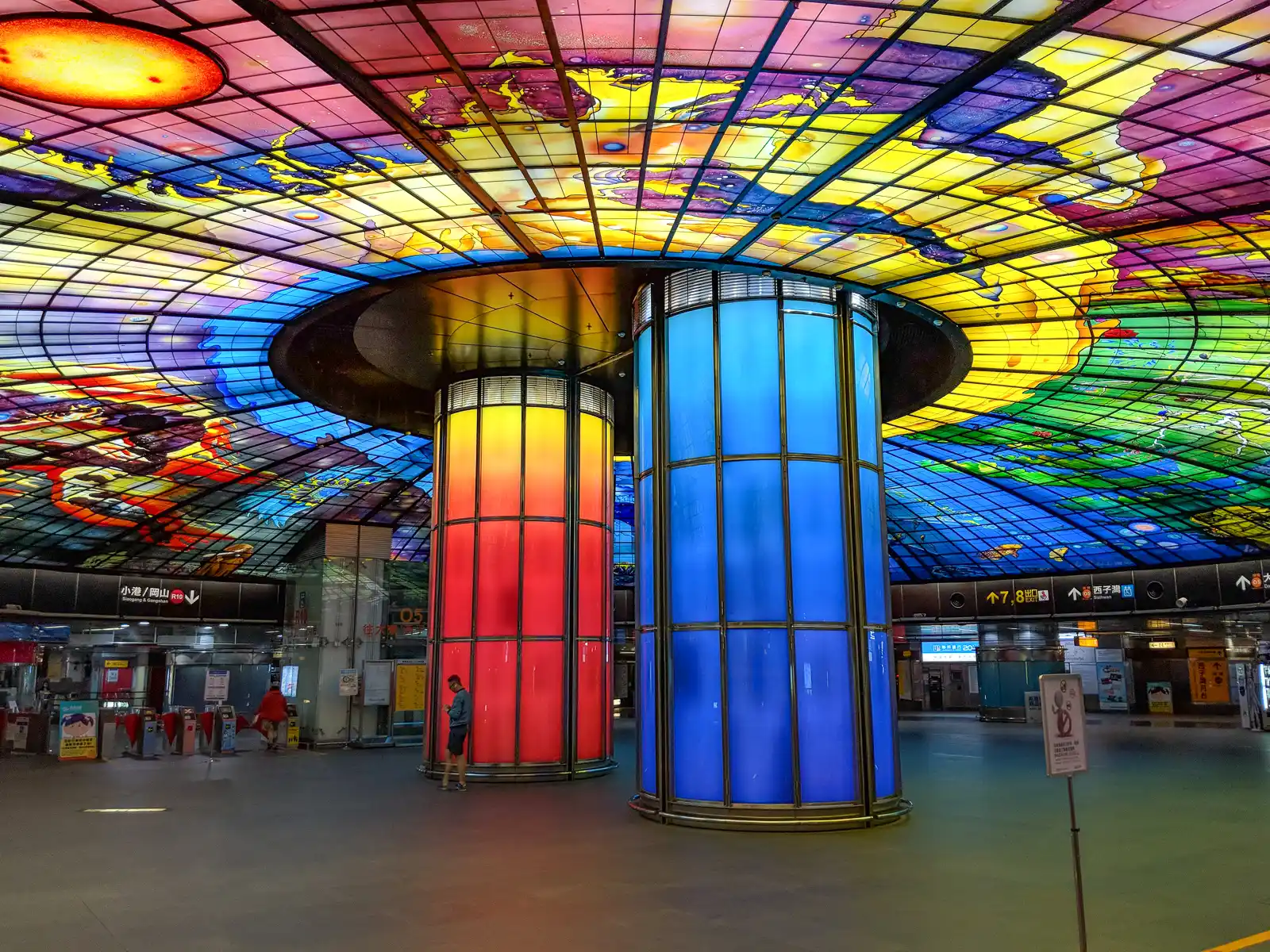 Two pillars support a vibrantly colored stained-glass ceiling.