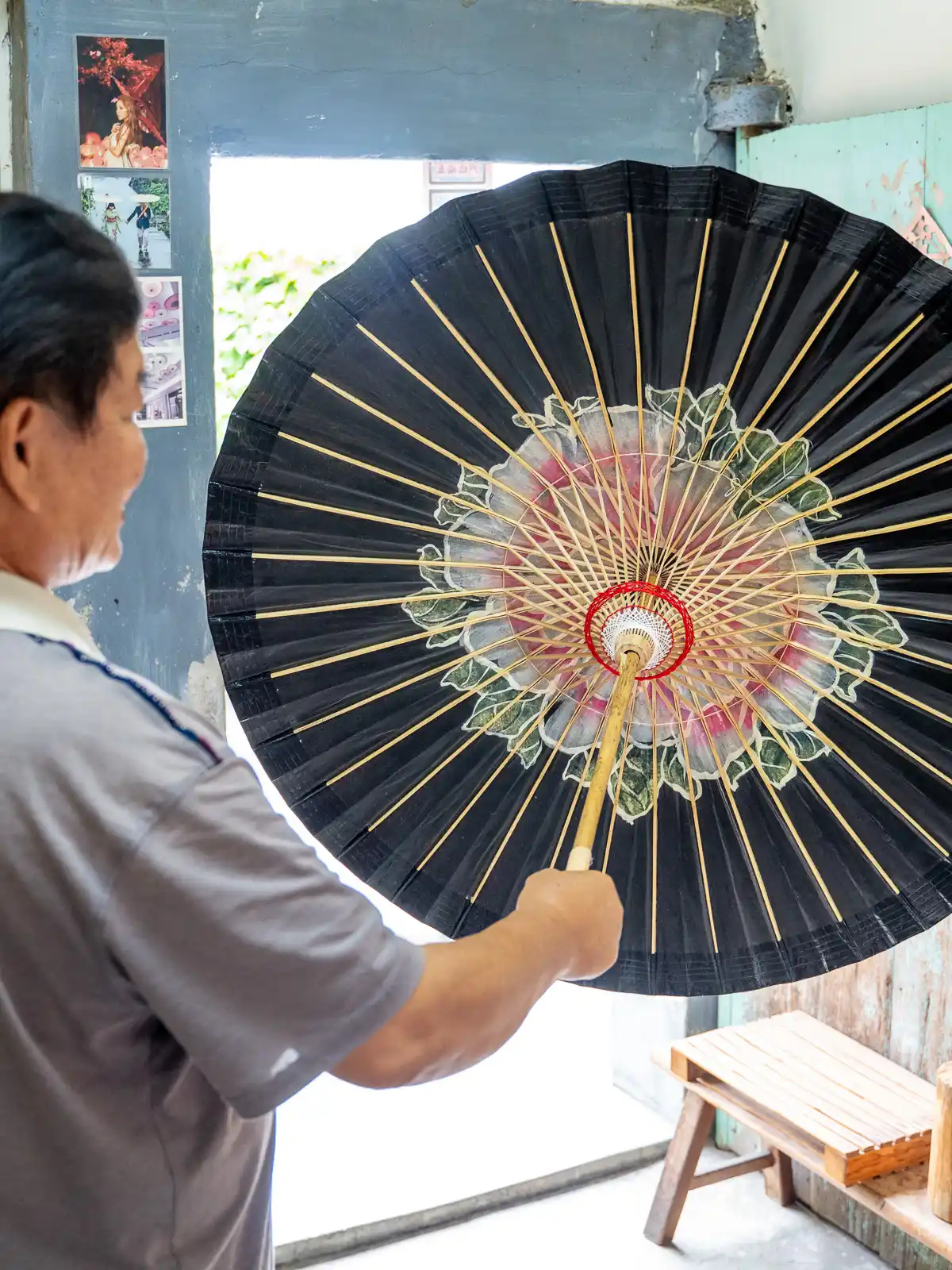A man shows the complex bamboo structure that supports the underside of an oil-paper umbrella.